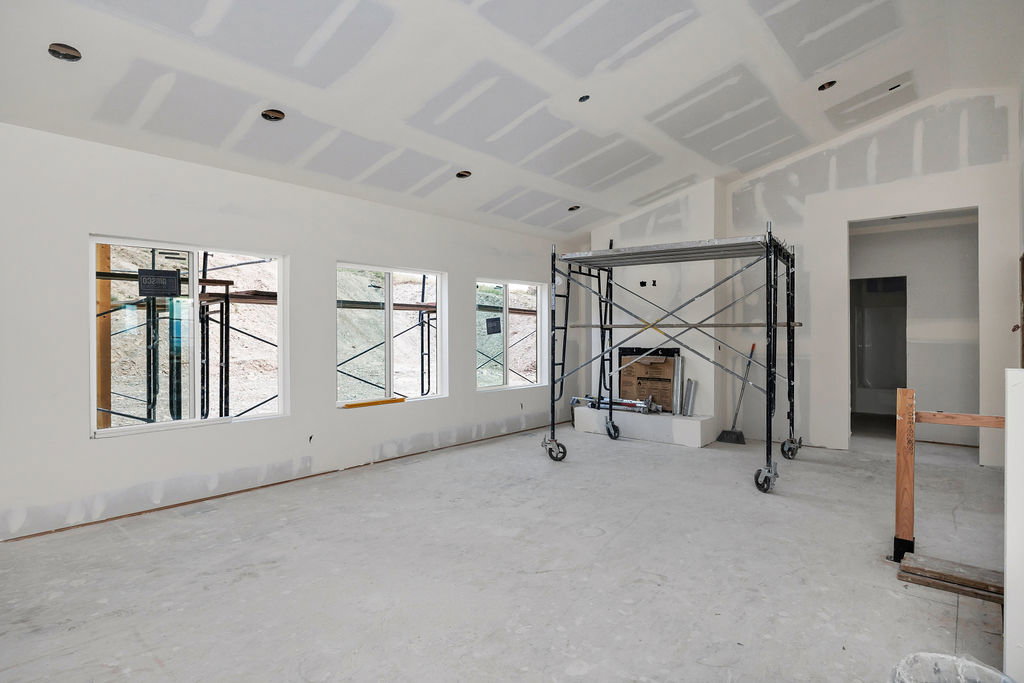 Spacious interior featuring multiple windows, a corner fireplace, vaulted ceiling, and recessed lighting pre-installation
