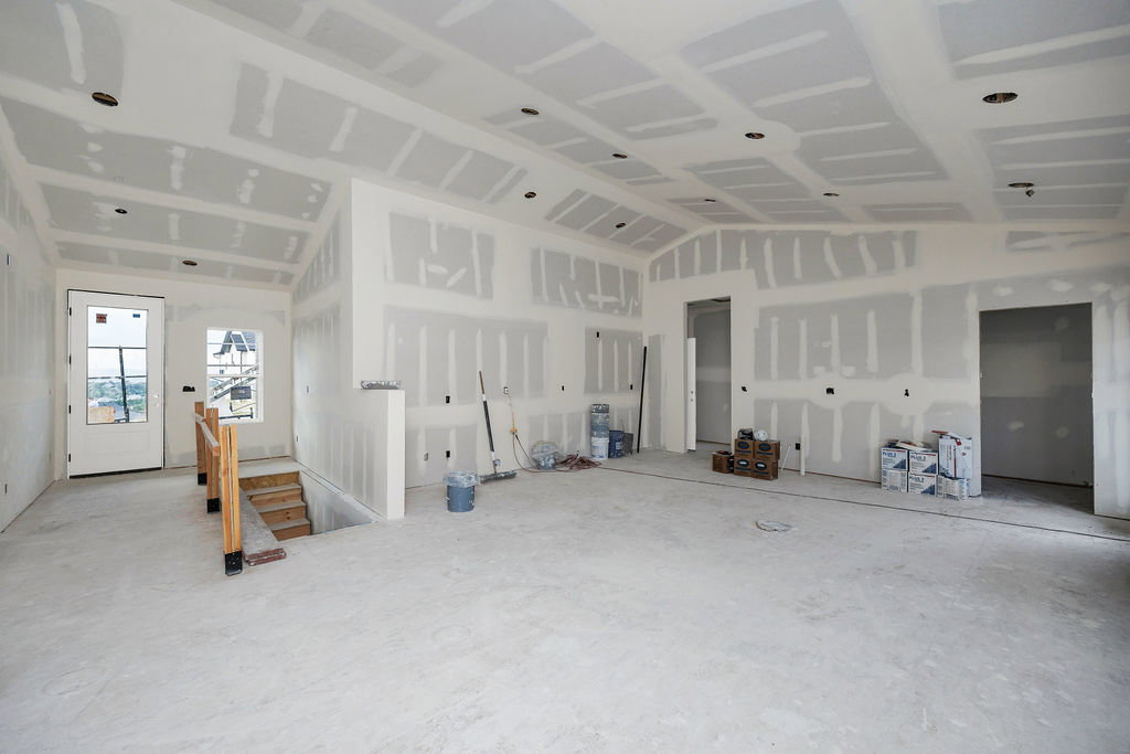 Spacious interior featuring high ceilings, recessed lighting, a door with multiple window panes, and a wooden handrail