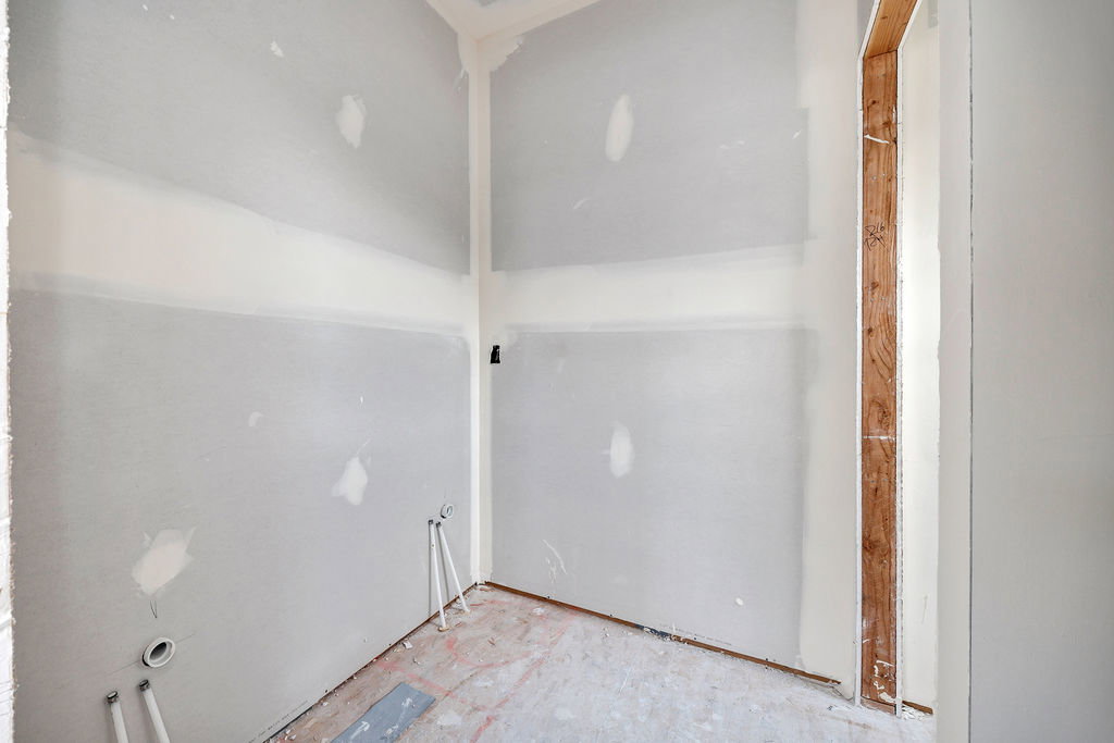 Interior space featuring unfinished drywall, exposed framing, and plumbing rough-ins