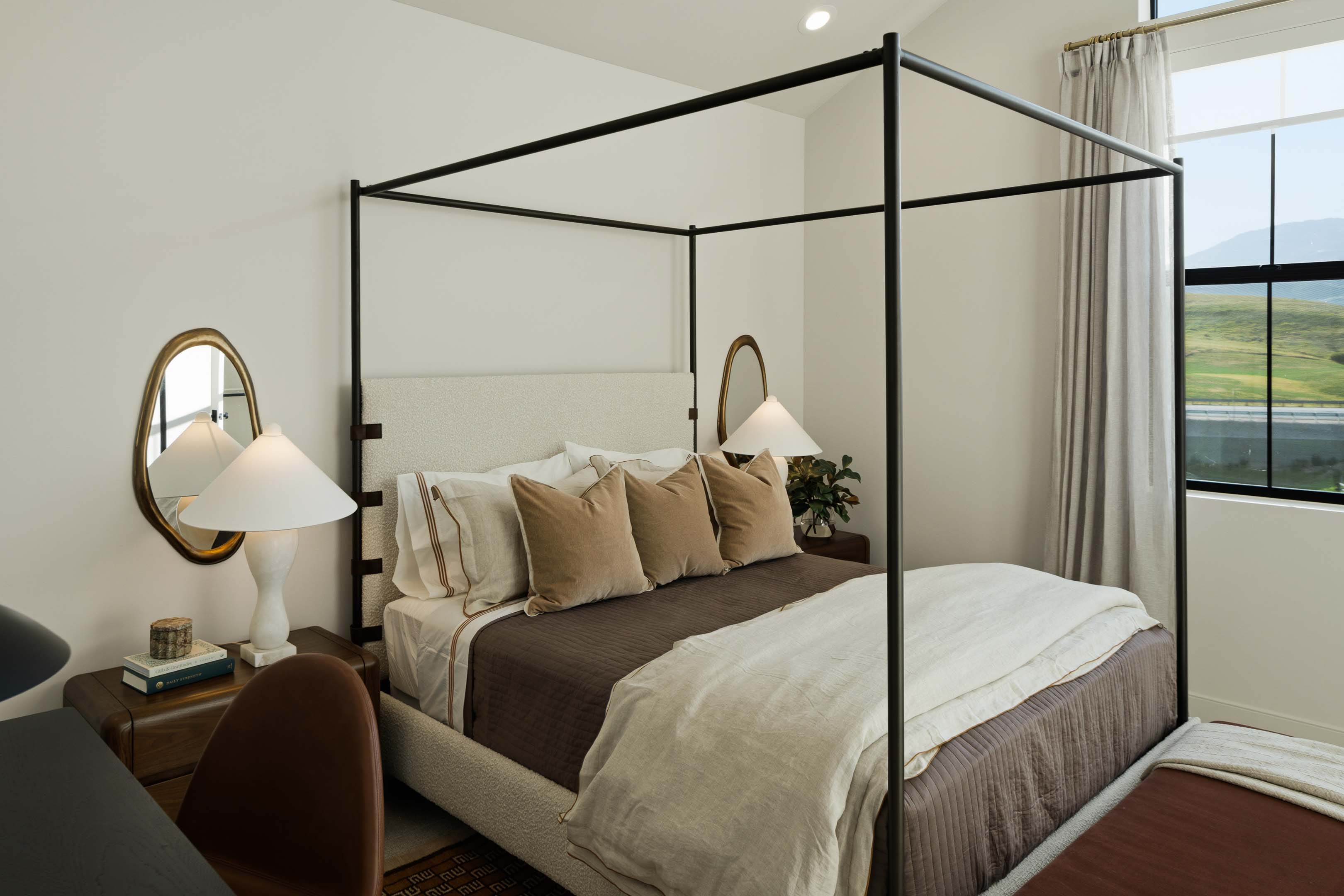 Bedroom featuring a black metal four-poster bed frame, upholstered headboard, and recessed lighting
