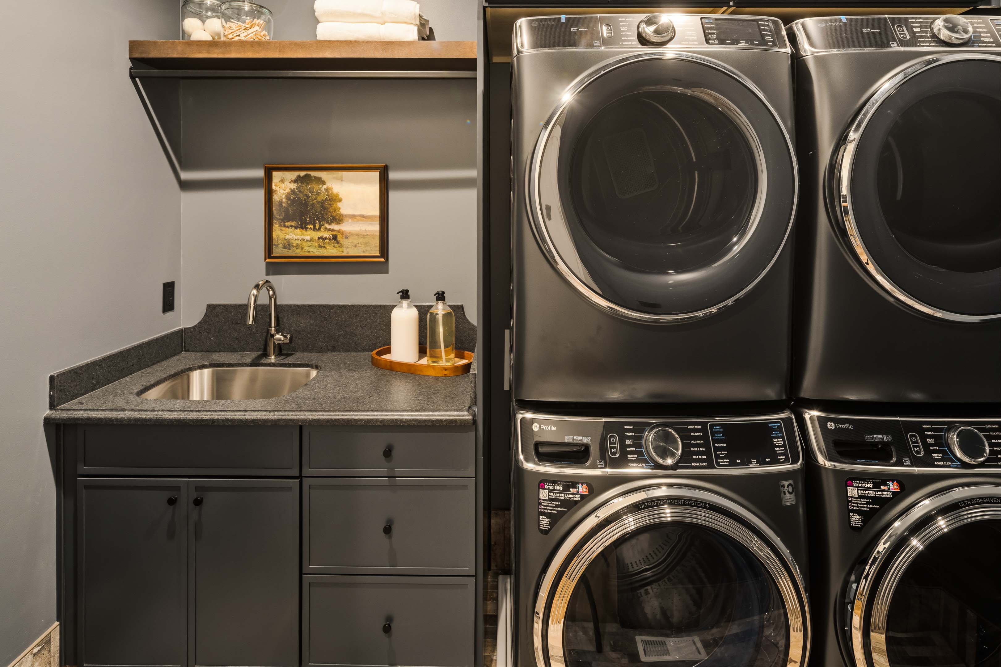 Laundry area featuring a built-in utility sink, dark cabinetry, and a dark stone-finish countertop