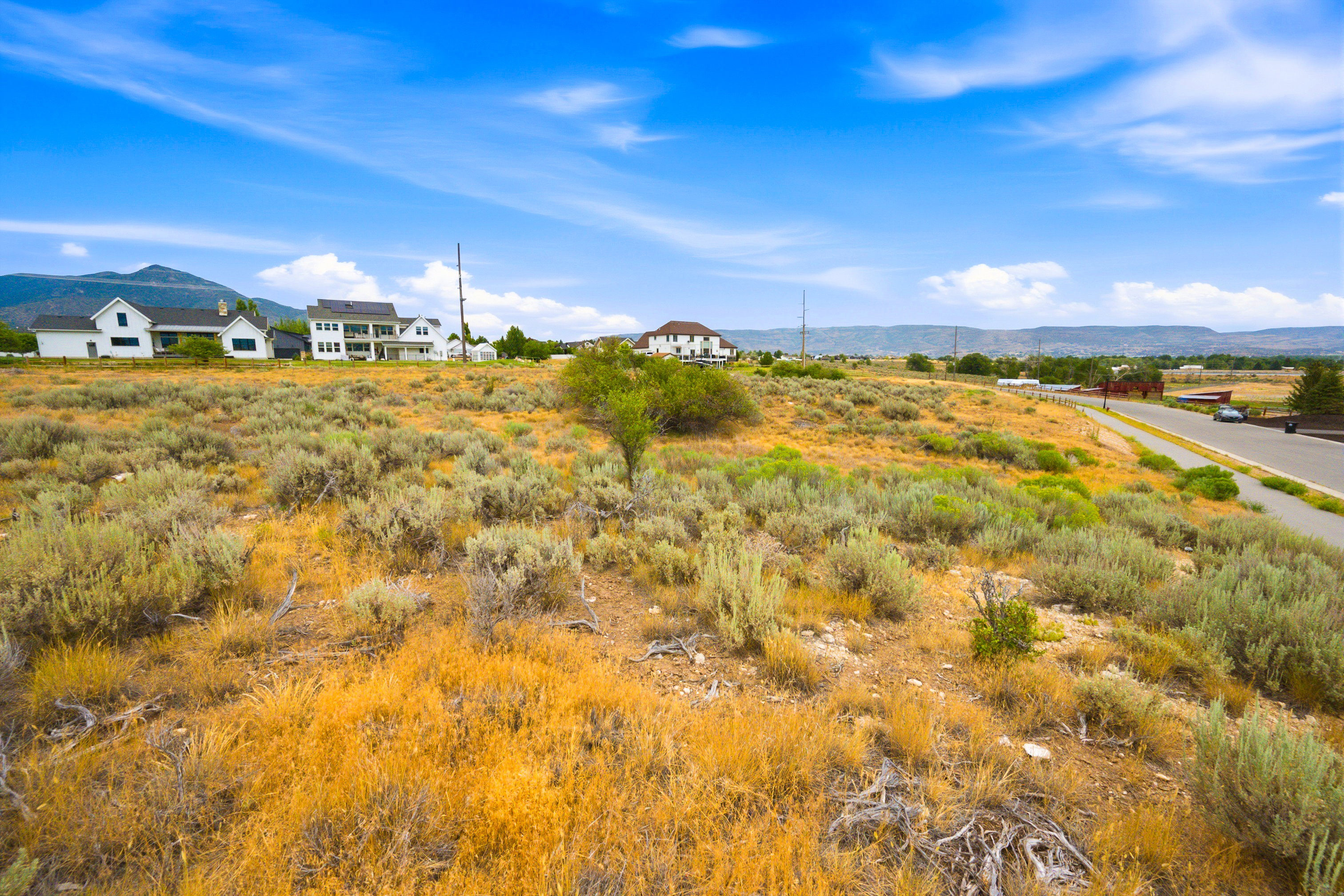 Expansive undeveloped land featuring natural shrubbery and a clear blue sky