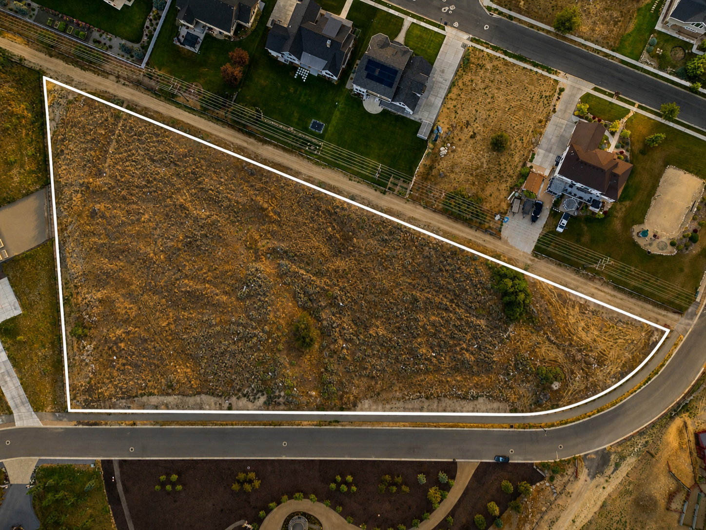 Expansive vacant lot featuring an irregular shape, a curved street frontage, and direct access to a paved road