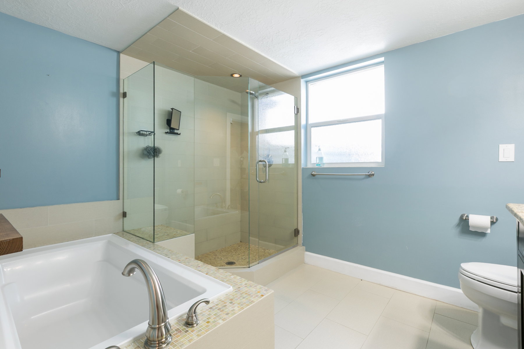 Bathroom featuring a spacious walk-in shower with glass enclosure, a built-in bathtub with tile surround, a large window, and ceramic tile flooring