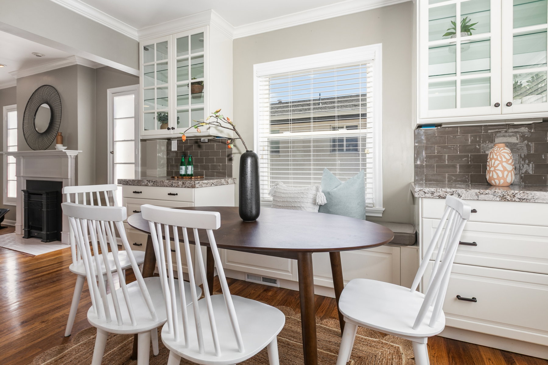 Built-in window bench seating complemented by white shaker-style cabinetry with glass-front upper cabinets