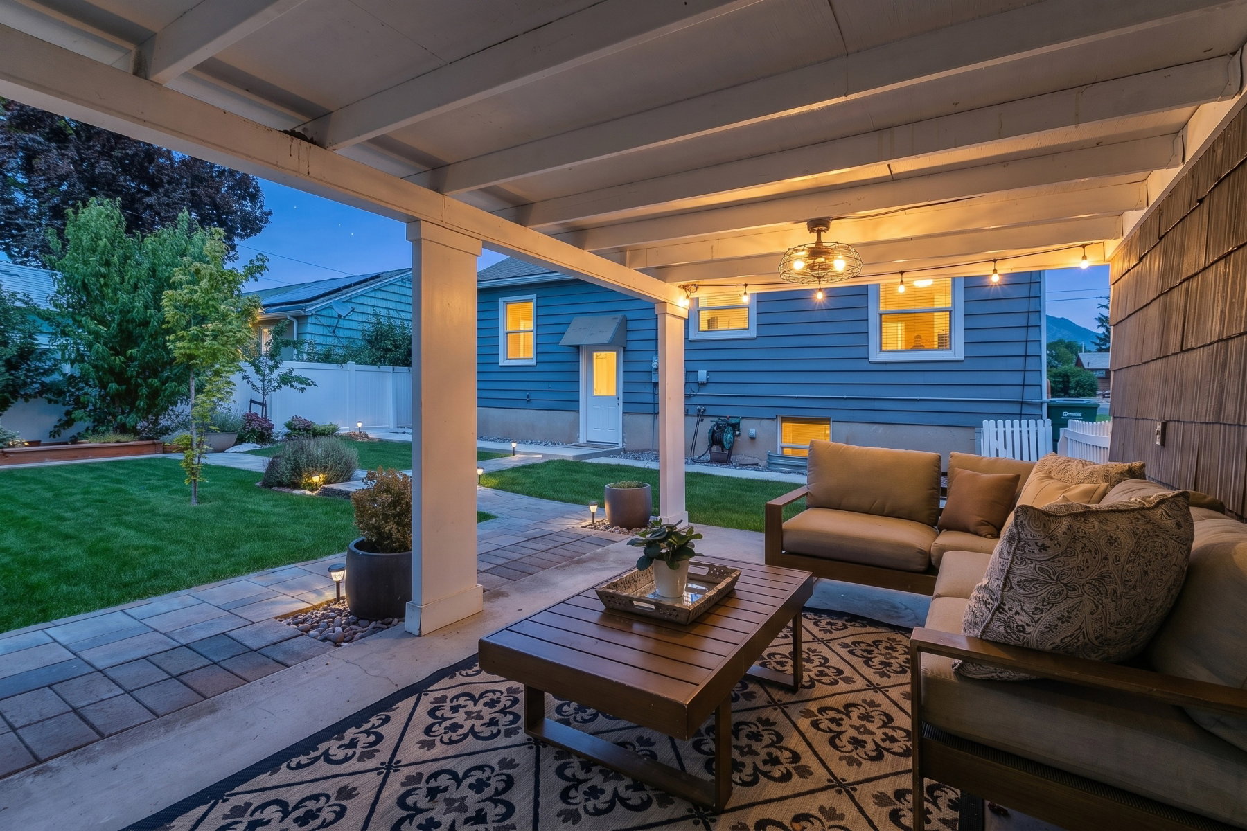 Covered patio featuring string lighting, a ceiling fan, and a wood-slat accent wall