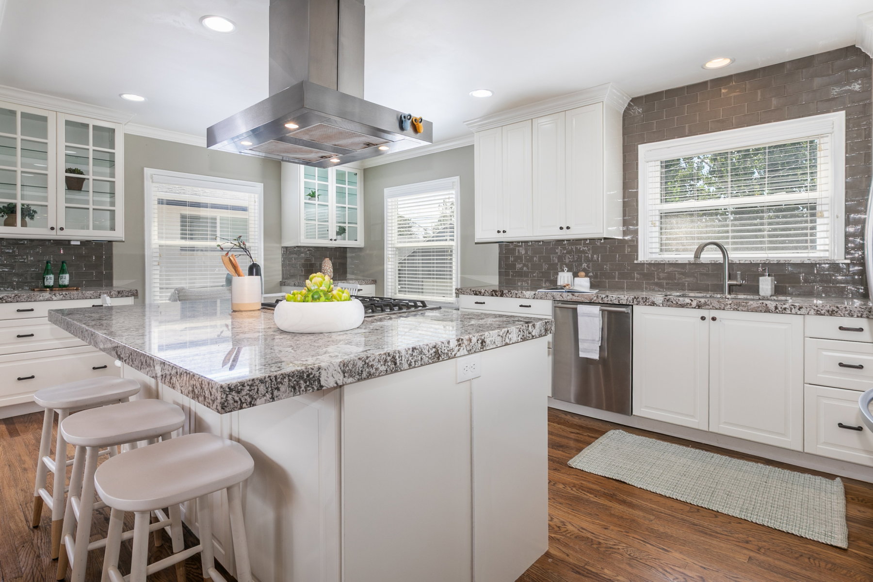 Expansive kitchen island with a granite countertop, white cabinetry, and a built-in cooktop