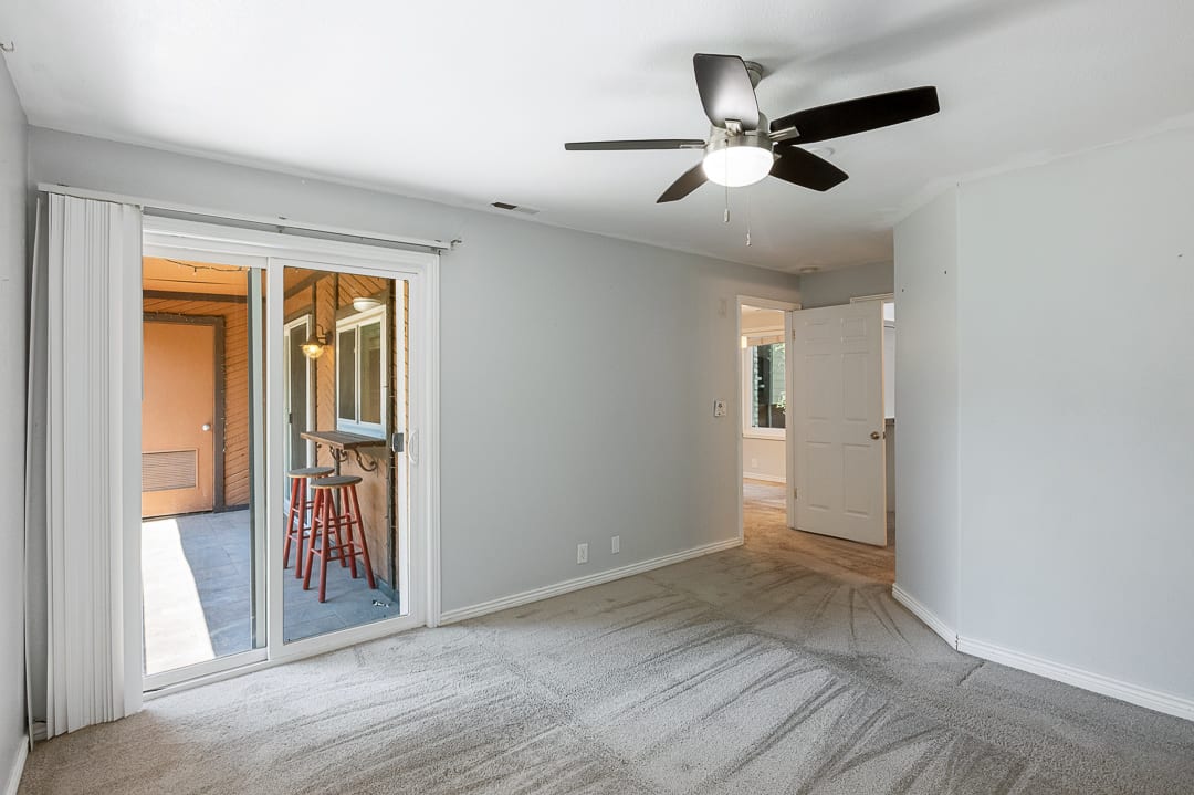 Room featuring light gray wall paint, gray carpeting, a contemporary ceiling fan with integrated lighting, and white baseboards