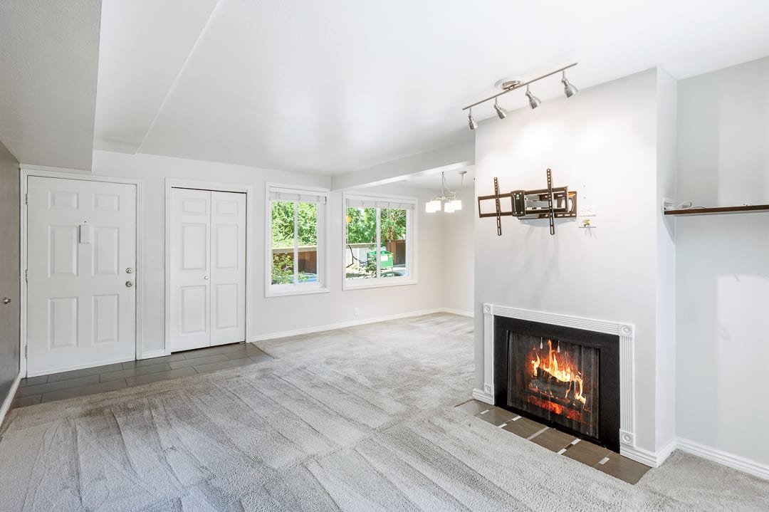 Living area featuring a fireplace with a white mantel, recessed shelving, track lighting, and two windows