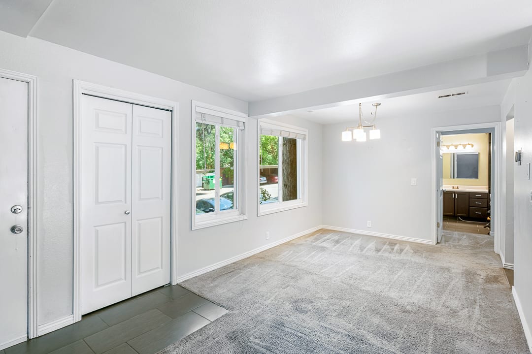 Open-concept living area featuring light gray carpeting and a contemporary four-light chandelier