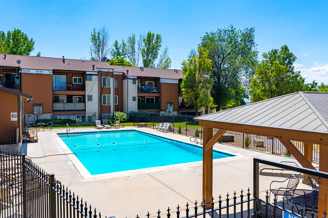 Outdoor swimming pool featuring a surrounding concrete deck and black wrought iron fencing