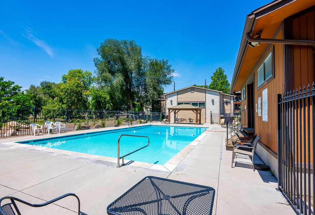 Community swimming pool featuring a concrete deck surround, metal handrails, and a perimeter fence
