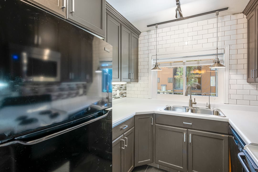Kitchen featuring a double basin stainless steel sink, solid surface countertops, and subway tile backsplash
