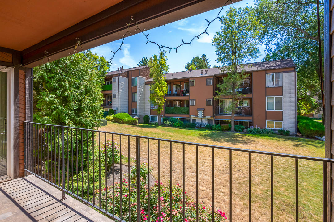 Private balcony with black wrought iron railing, offering exterior views of the surrounding apartment buildings and a central lawn area