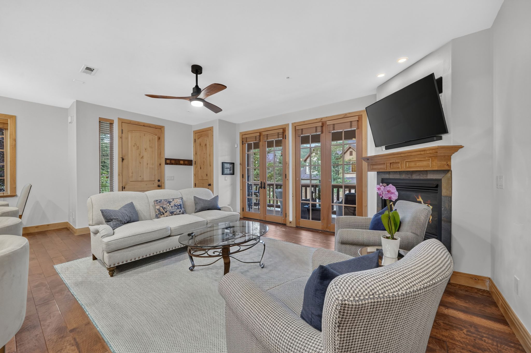 Living area featuring wood-finish flooring, a stone-clad fireplace with a wood mantel, and double French doors opening to an exterior space