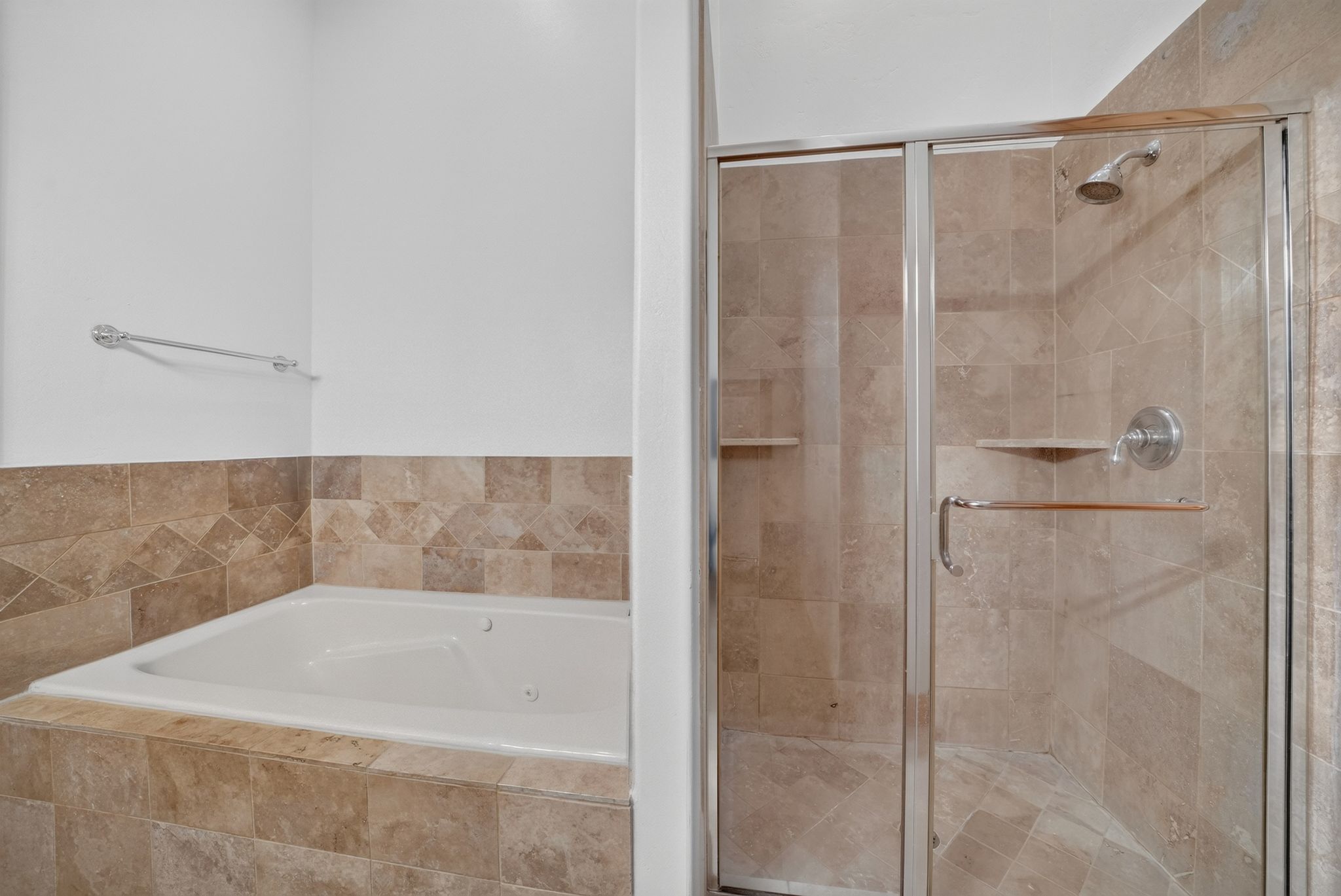 Bathroom featuring a tiled soaking tub and a separate glass-enclosed shower