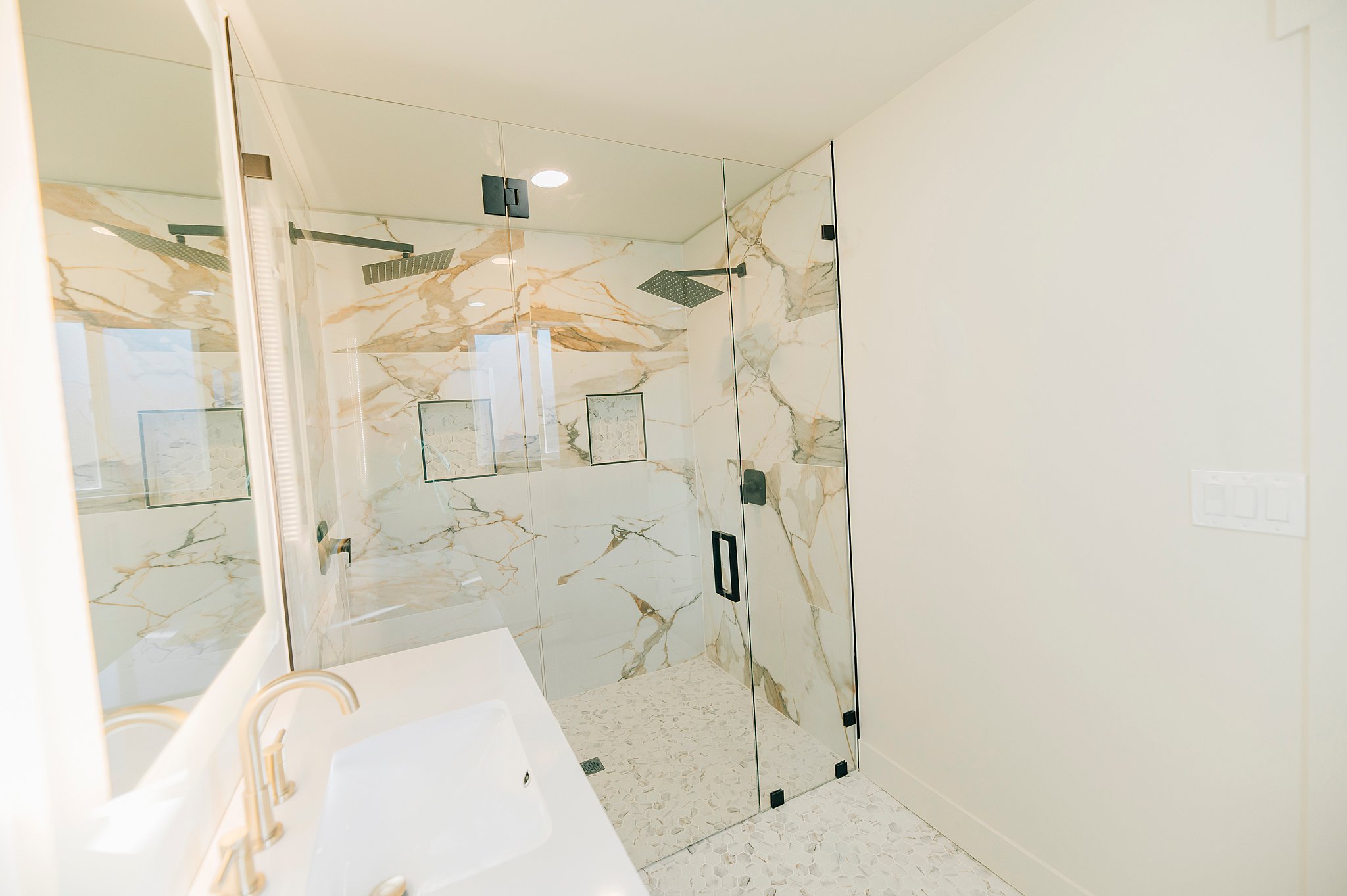 Spacious walk-in shower with clear glass enclosure and dual rain-style shower heads