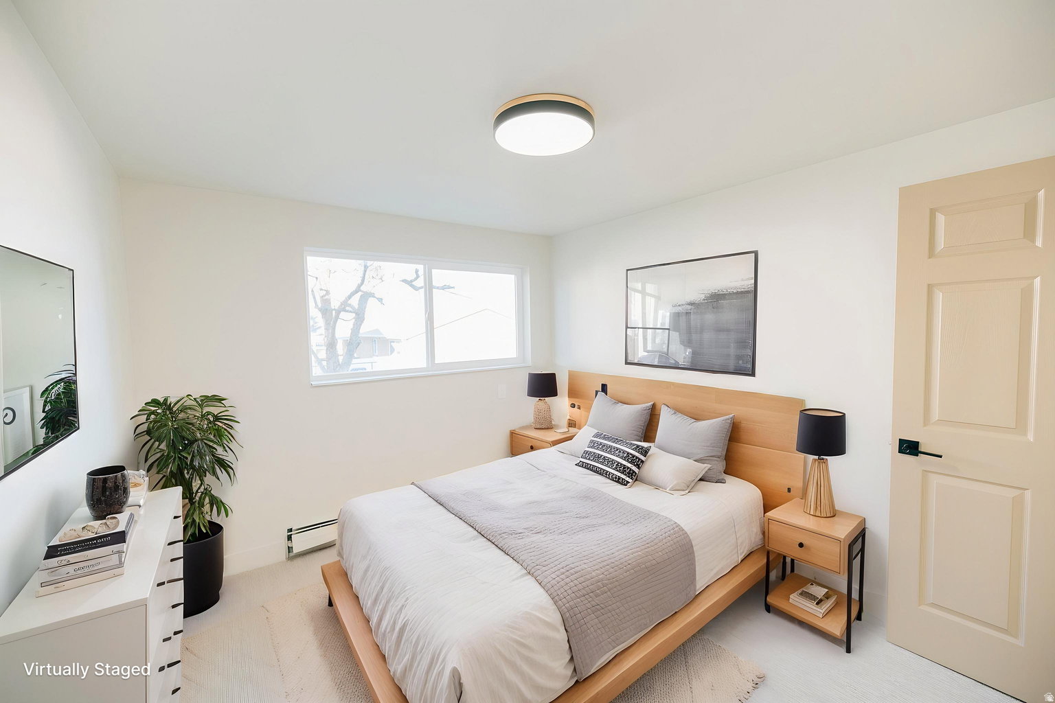 Bedroom featuring light-toned wood-finish flooring, a contemporary flush-mount ceiling light, a multi-pane window, a paneled door with matte black hardware, and bright white walls