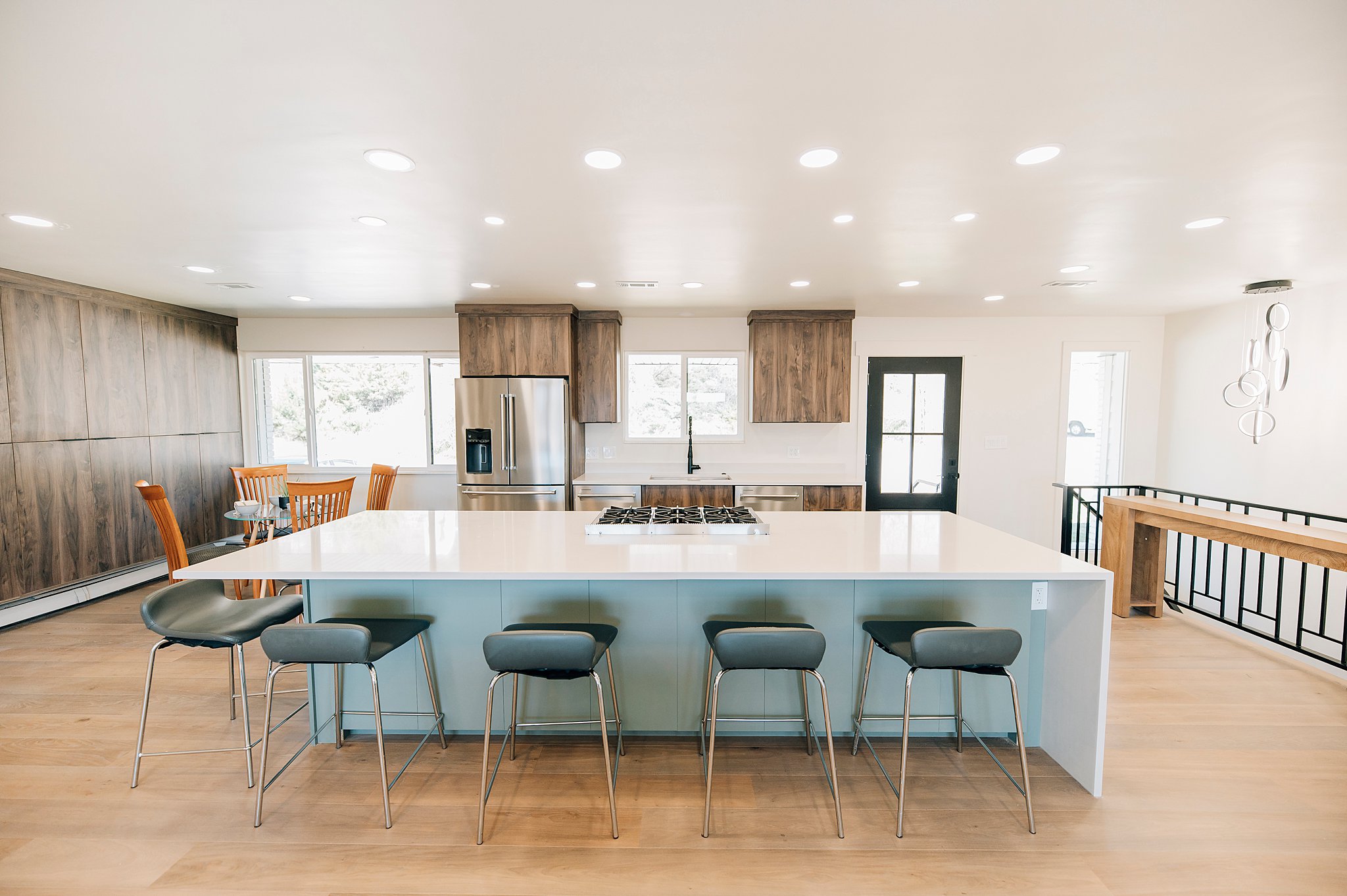 Spacious kitchen featuring a large island with a cooktop, quartz countertops, stainless steel appliances, wood-finish flooring, and recessed lighting