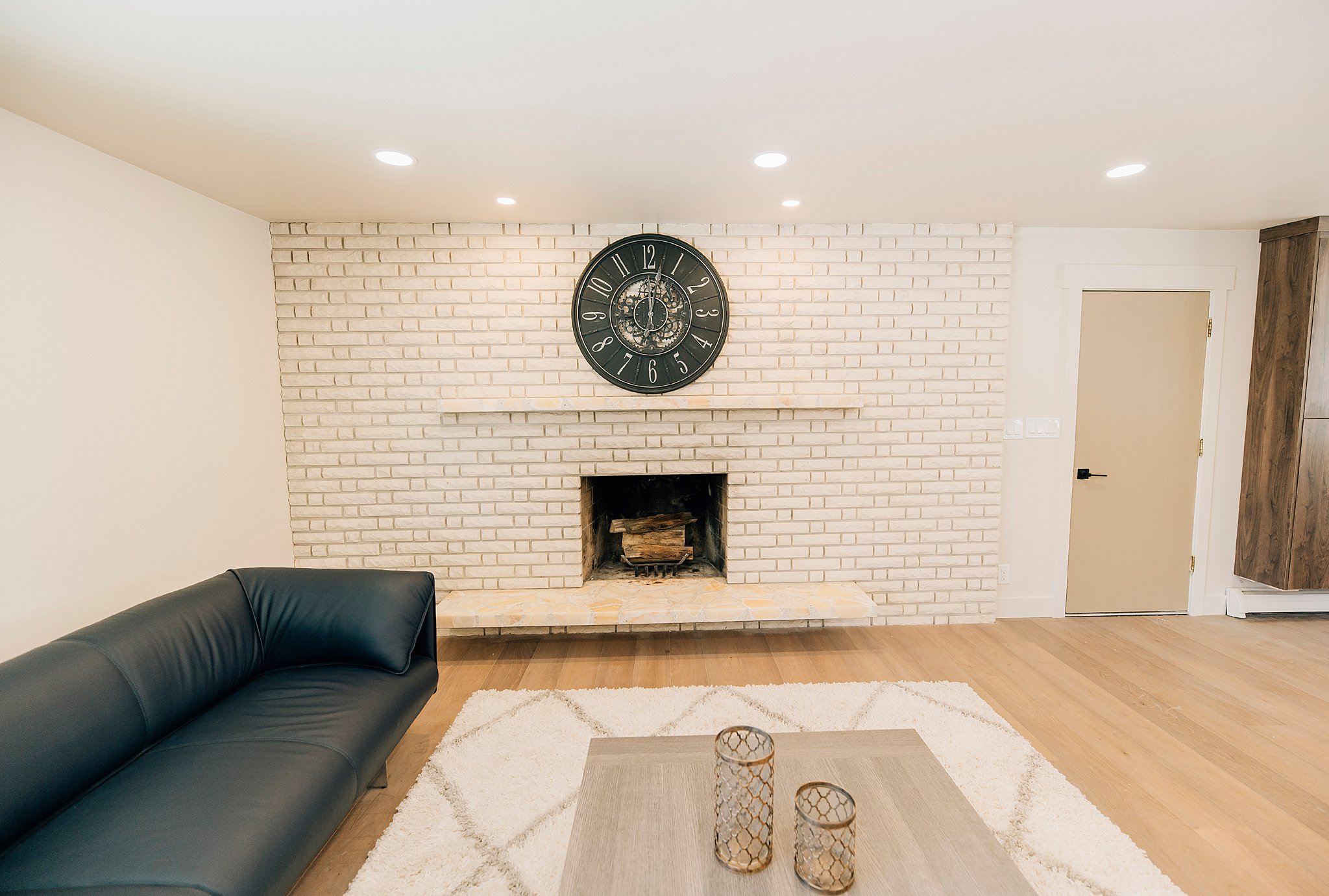 Living area featuring a painted brick fireplace with a stone hearth, recessed lighting, and light wood-finish flooring