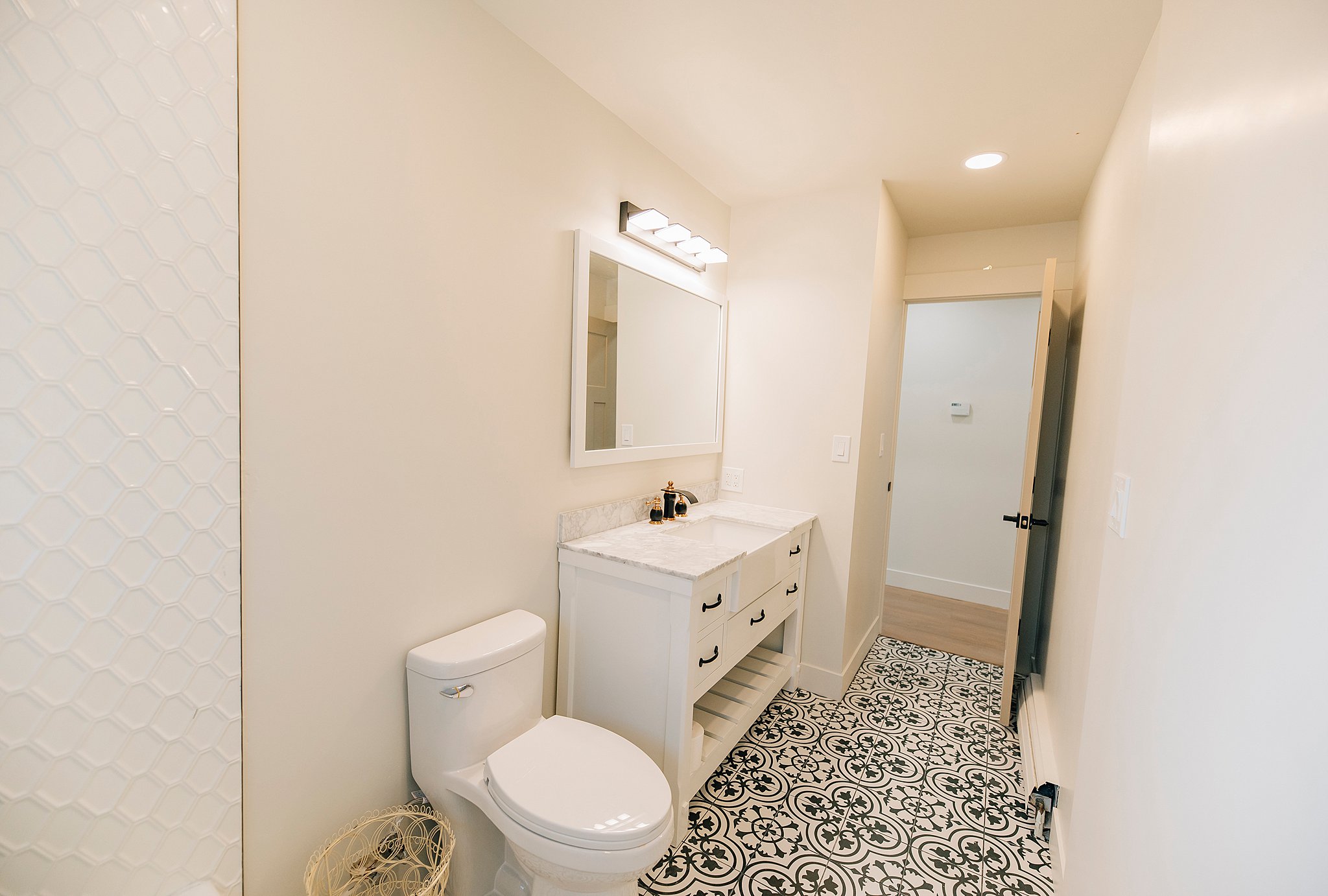 Bathroom featuring patterned floor tiles, a white vanity with a light-colored countertop, and a rectangular mirror with overhead lighting