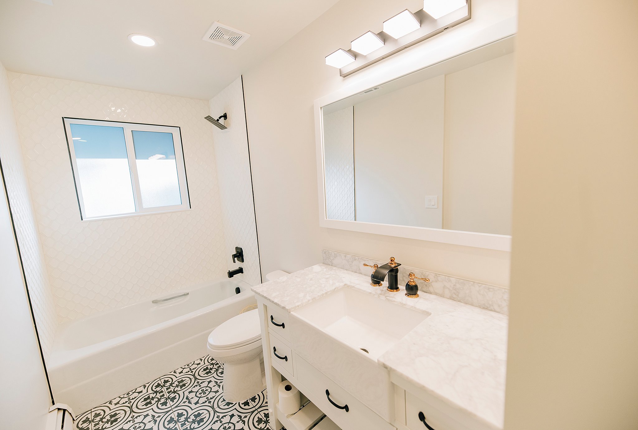 Bathroom featuring a vanity with a rectangular undermount sink, a stone countertop, and custom tile flooring