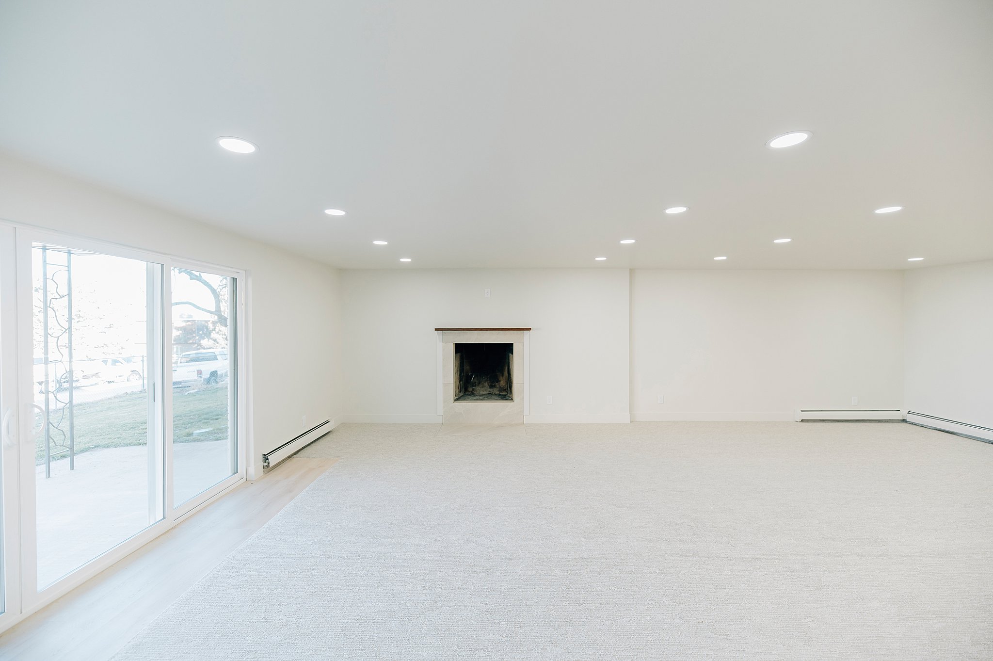 Spacious interior featuring a fireplace with a wood mantle, recessed lighting, and light-colored carpeting