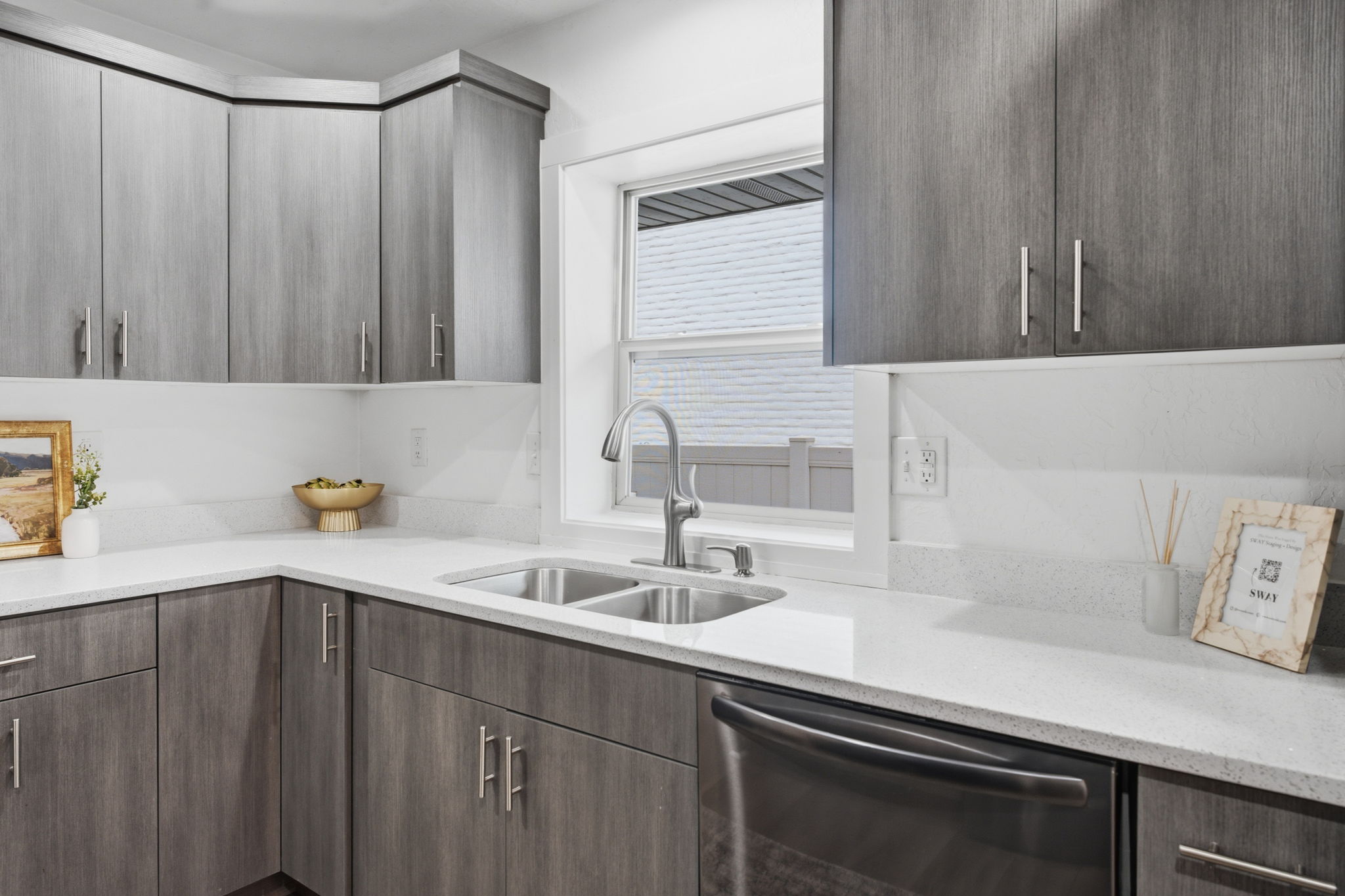 Kitchen featuring wood-finish cabinetry with modern hardware, white countertops, and a double basin stainless steel sink with a gooseneck faucet