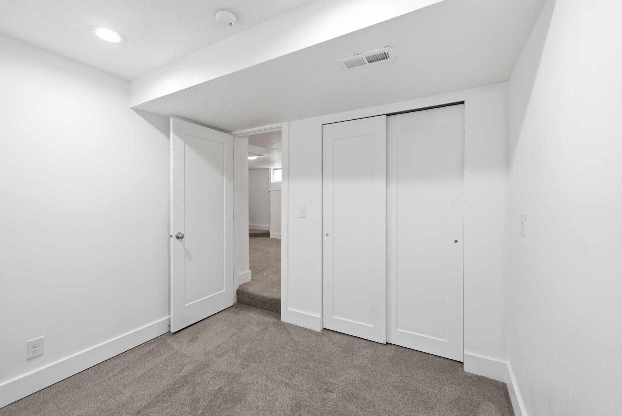 Room featuring neutral gray carpet, white walls, and bright recessed lighting