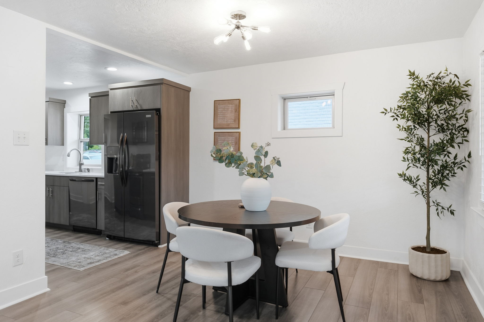 Dining area featuring wood-finish flooring, a contemporary chandelier, and a compact window
