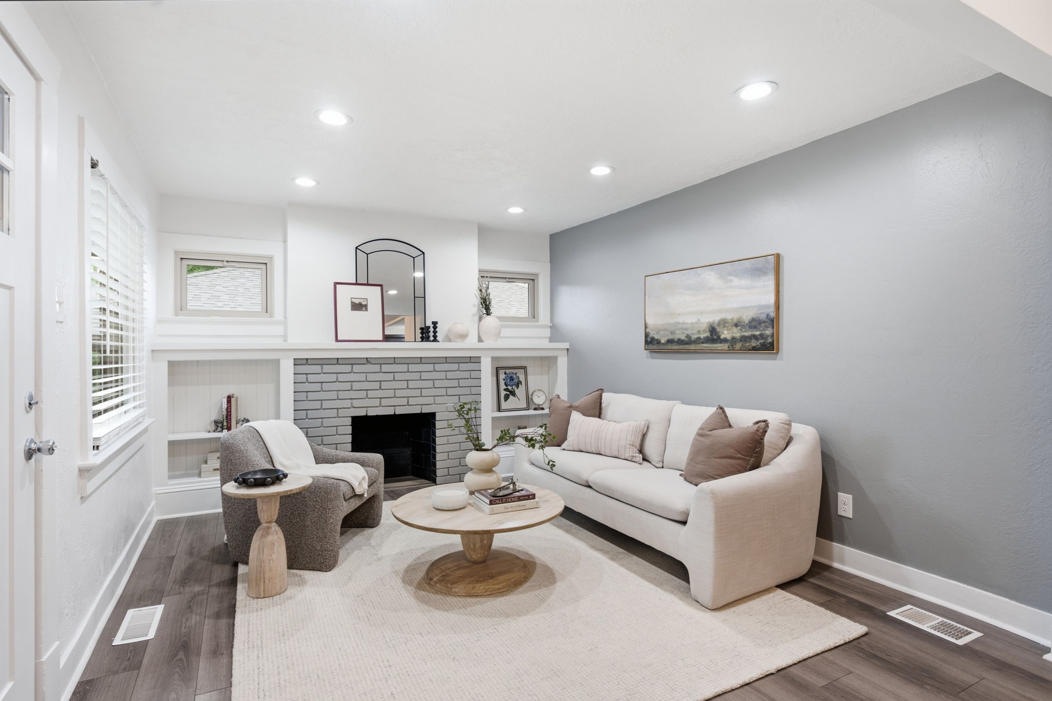 Living area featuring a painted brick fireplace with a mantel, built-in shelving, wood-finish flooring, and recessed lighting