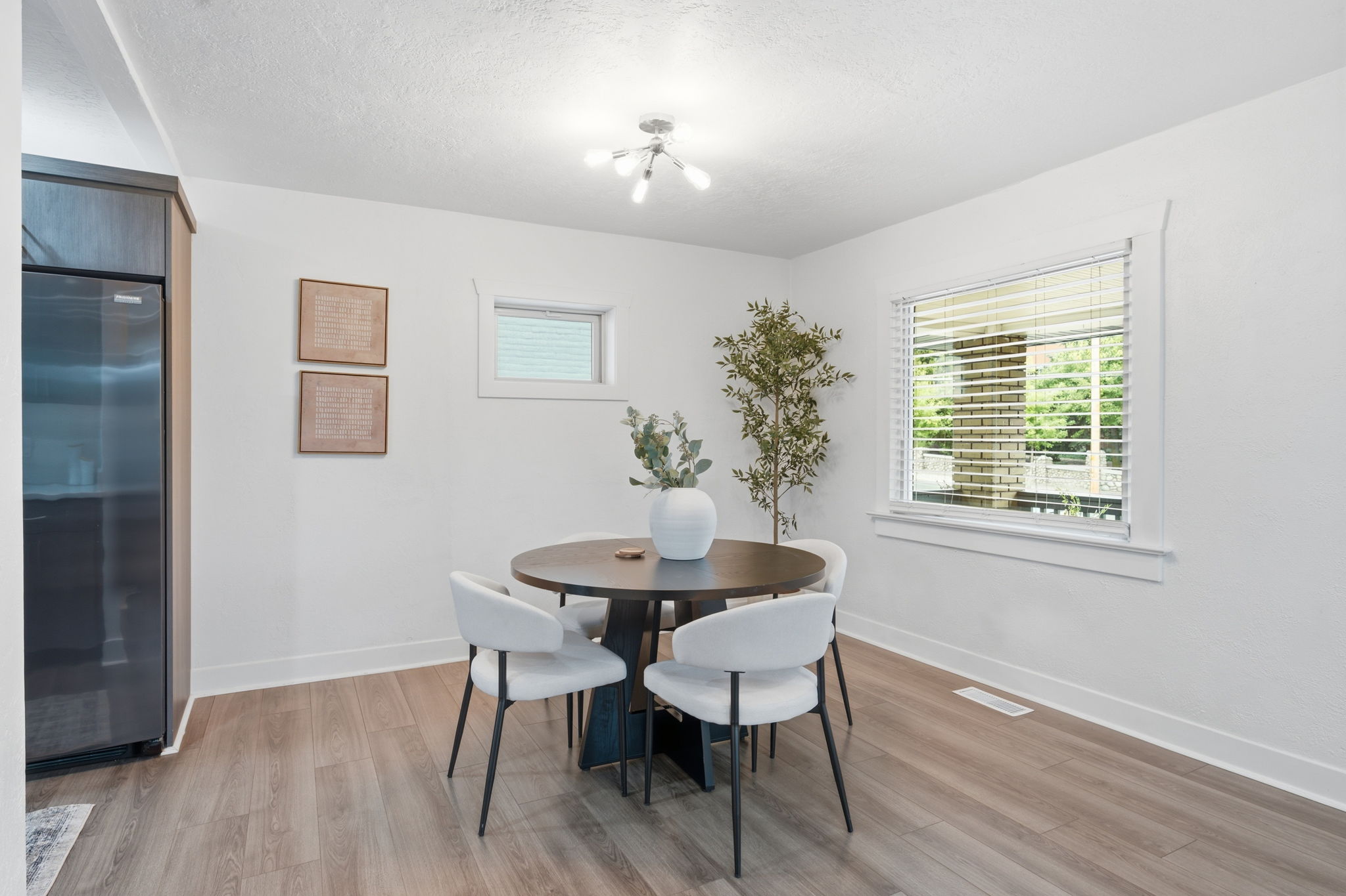 Dining space featuring wood-finish flooring, a large window with blinds, and white trim