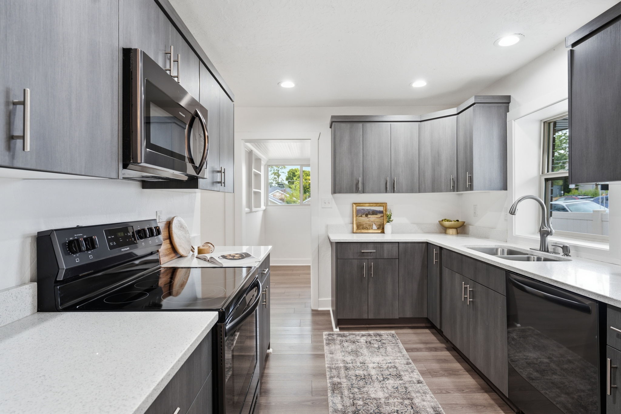 Modern kitchen featuring L-shaped wood-finish cabinetry, white countertops, stainless steel appliances, and recessed lighting