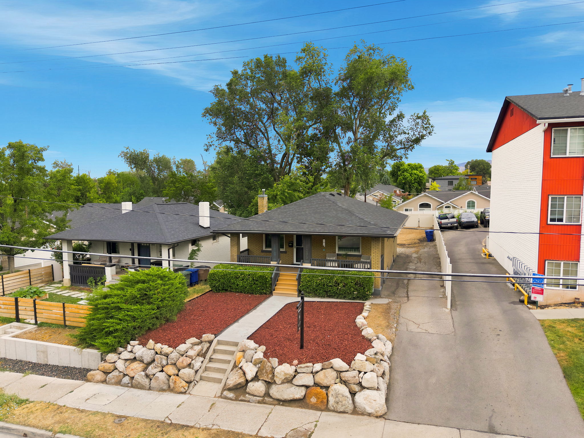 Front facade featuring a stone retaining wall, concrete walkway, and landscaped yard with red mulch and green shrubs