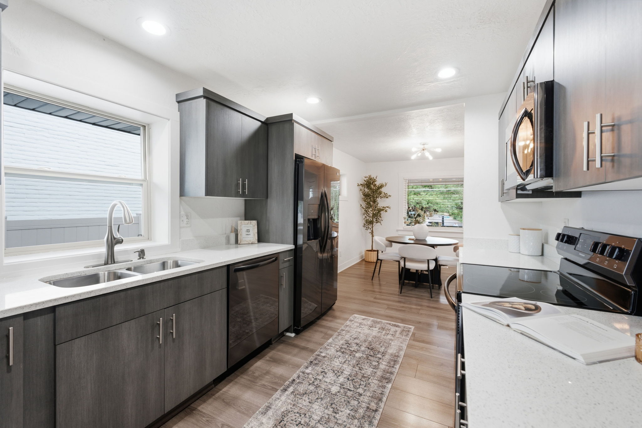 Modern kitchen featuring wood-finish cabinetry, light countertops, and dark stainless steel appliances