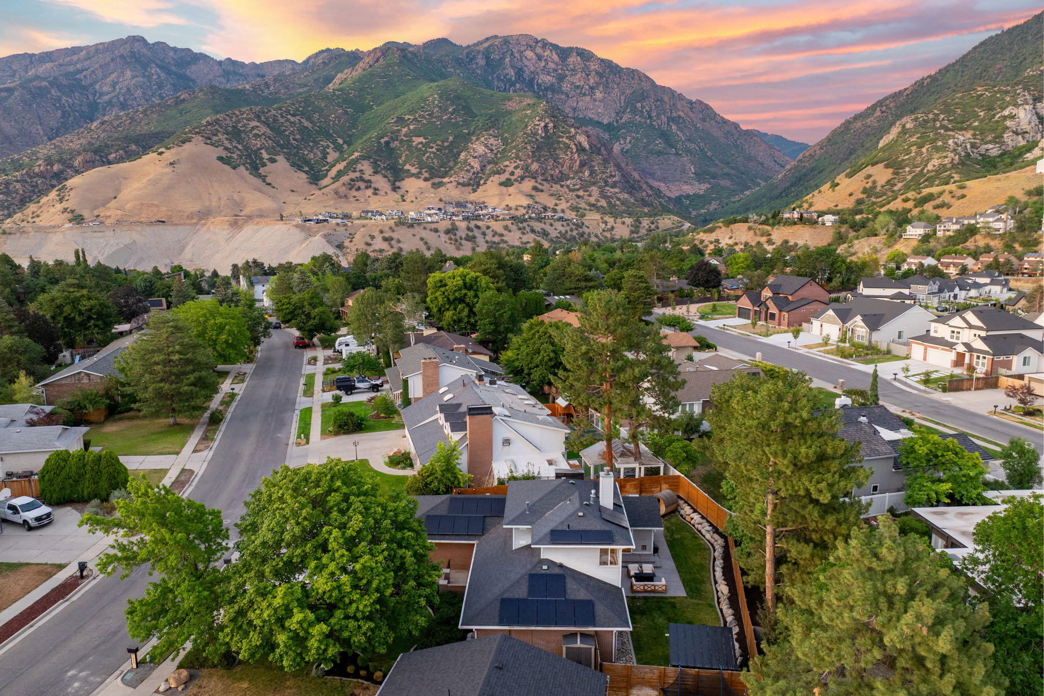 Residential neighborhood with mature trees, established streets, and mountain terrain in the background