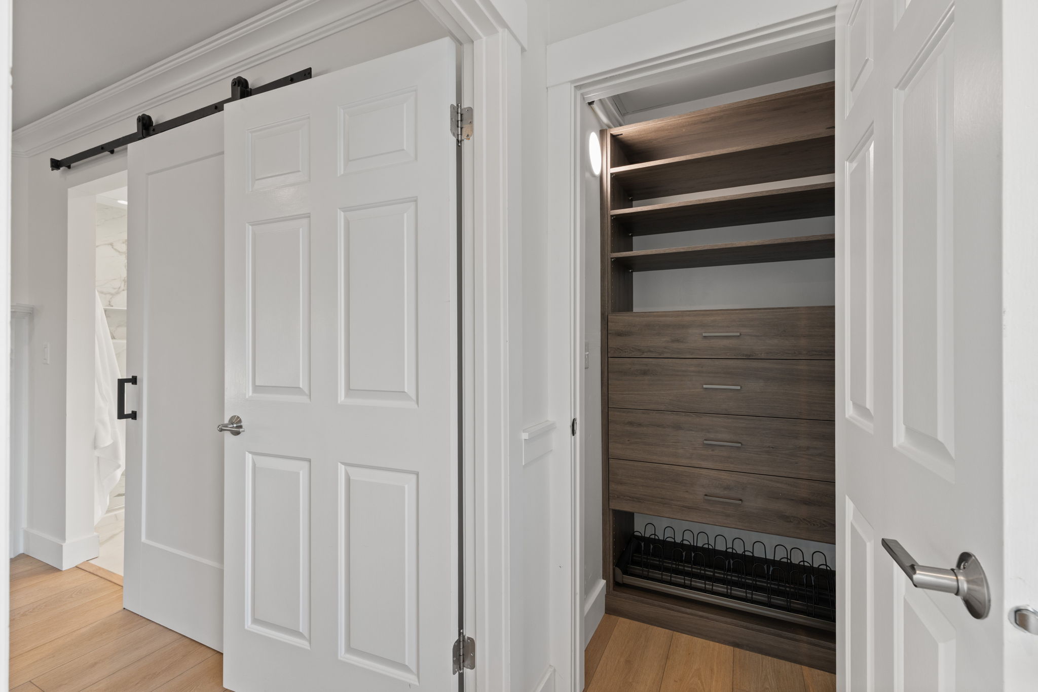 Built-in closet system featuring wood-finish shelving, drawers with brushed nickel hardware, and a shoe rack