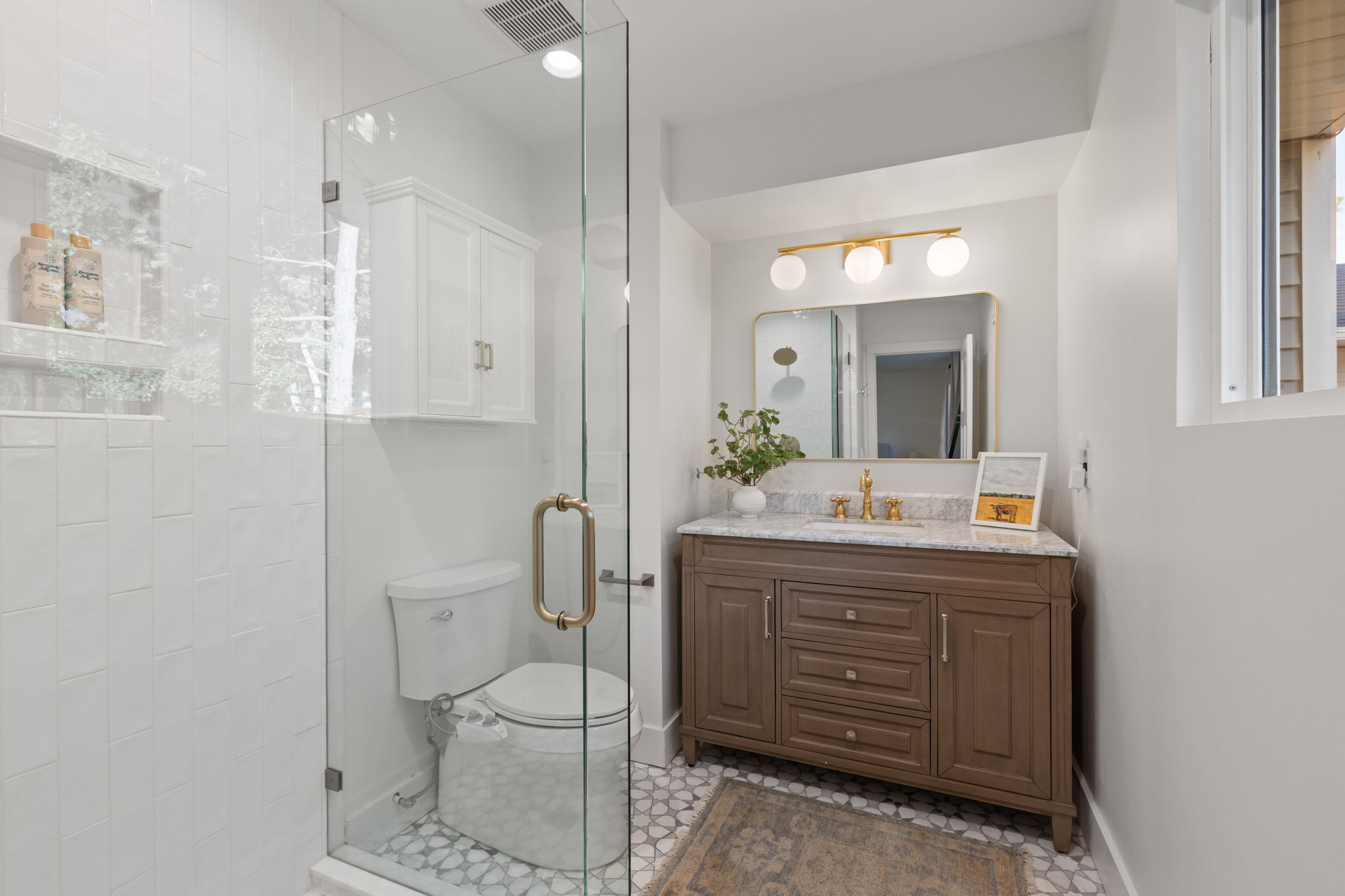 Bathroom featuring a glass-enclosed shower, a vanity with a stone countertop, a gold-finished faucet, and a contemporary light fixture