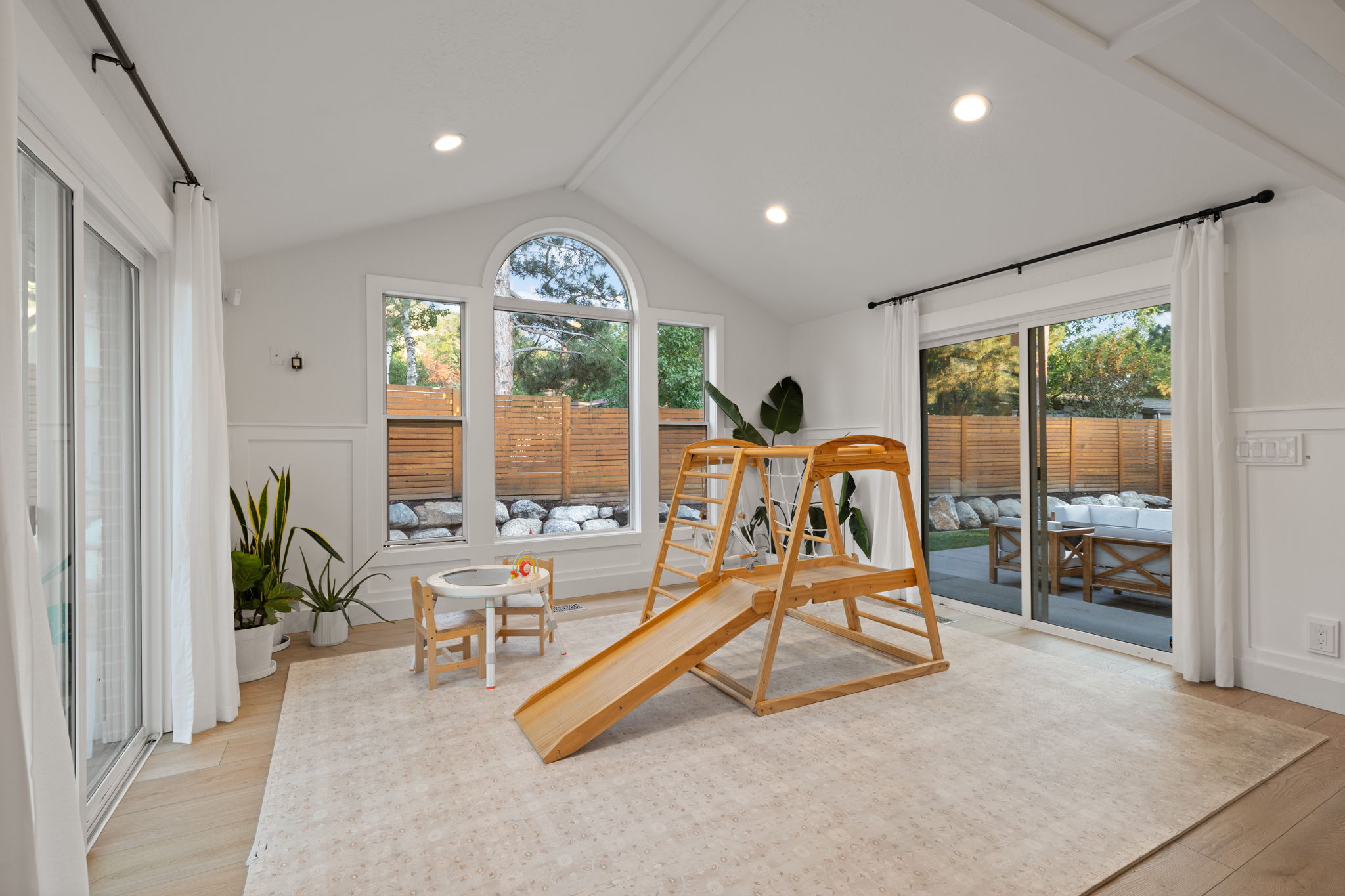 Vaulted ceiling interior space featuring recessed lighting, paneled wall detailing, and wood-finish flooring