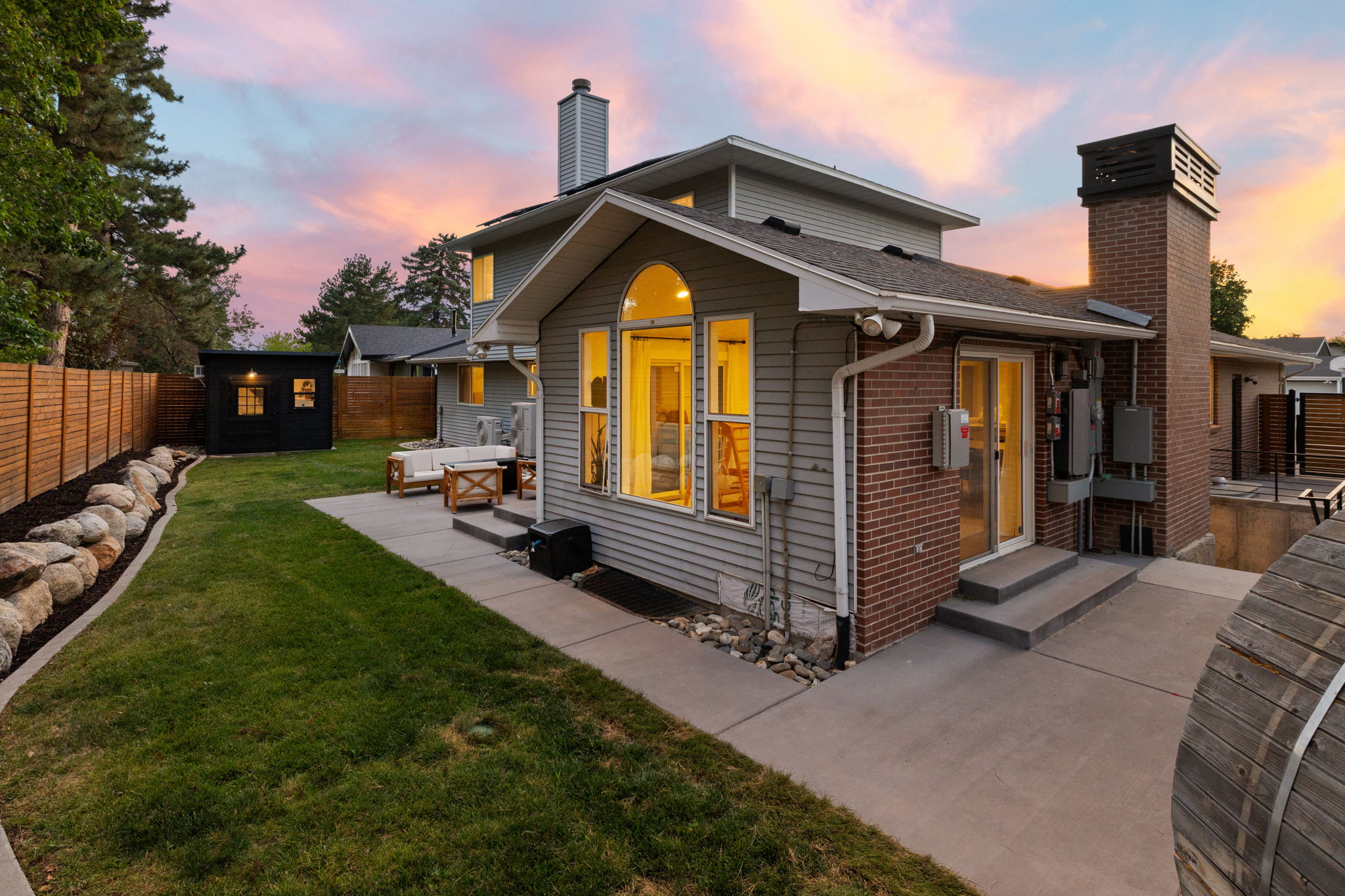 Expansive backyard featuring a manicured lawn, a detached shed, a full privacy fence, and a concrete patio