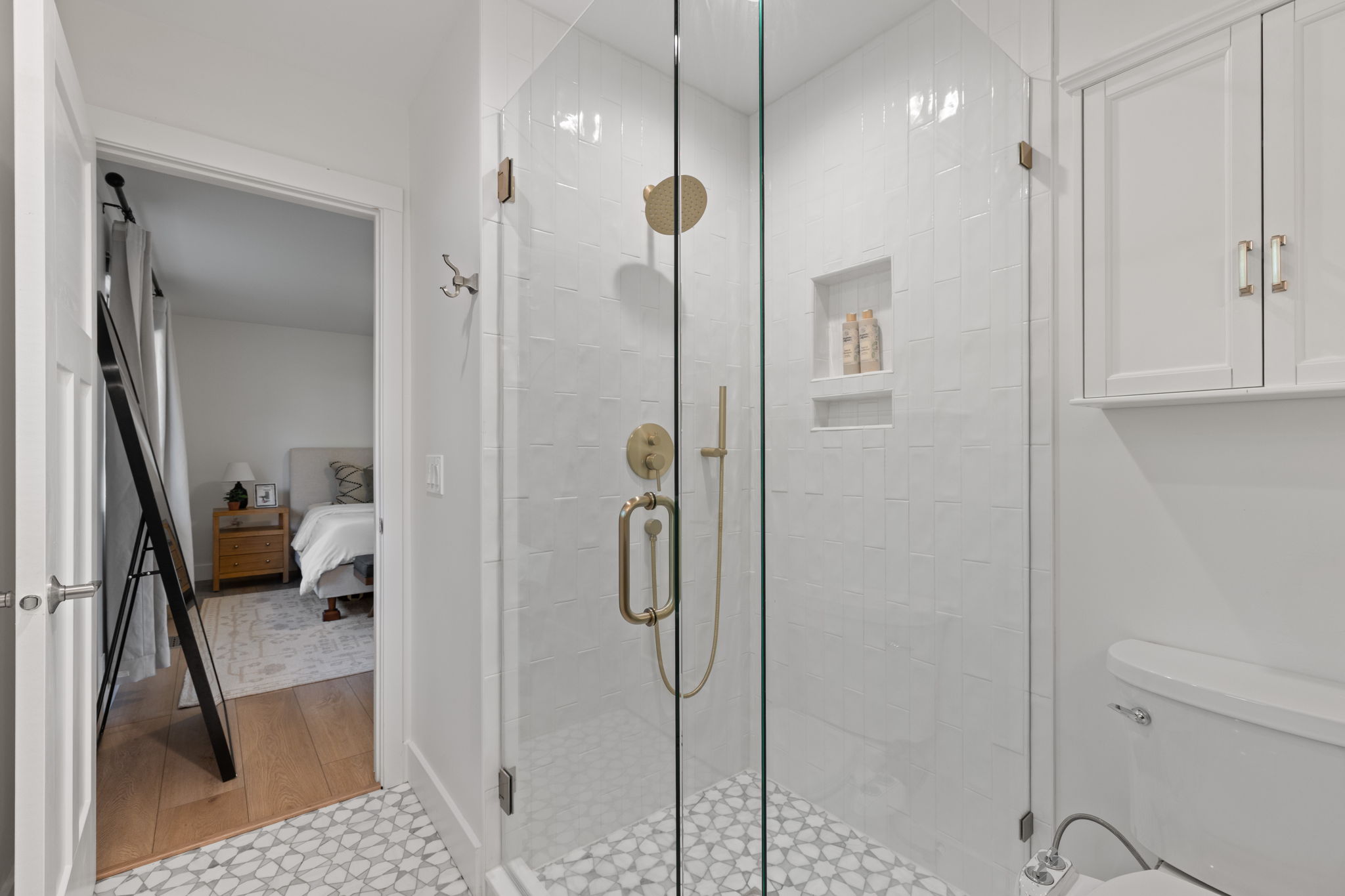 Contemporary shower enclosure featuring clear glass panels and gold-tone fixtures