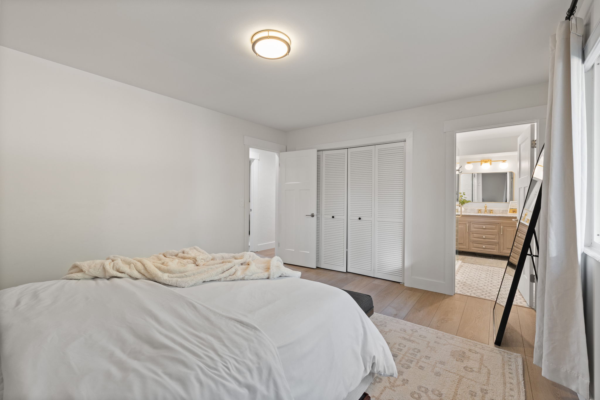 Bedroom with light wood-finish flooring, white walls, and a contemporary flush-mount ceiling light