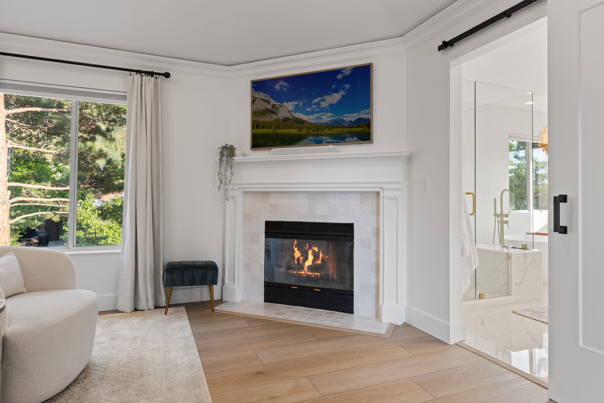 Wood-finish flooring with a fireplace featuring a white mantel and tile surround