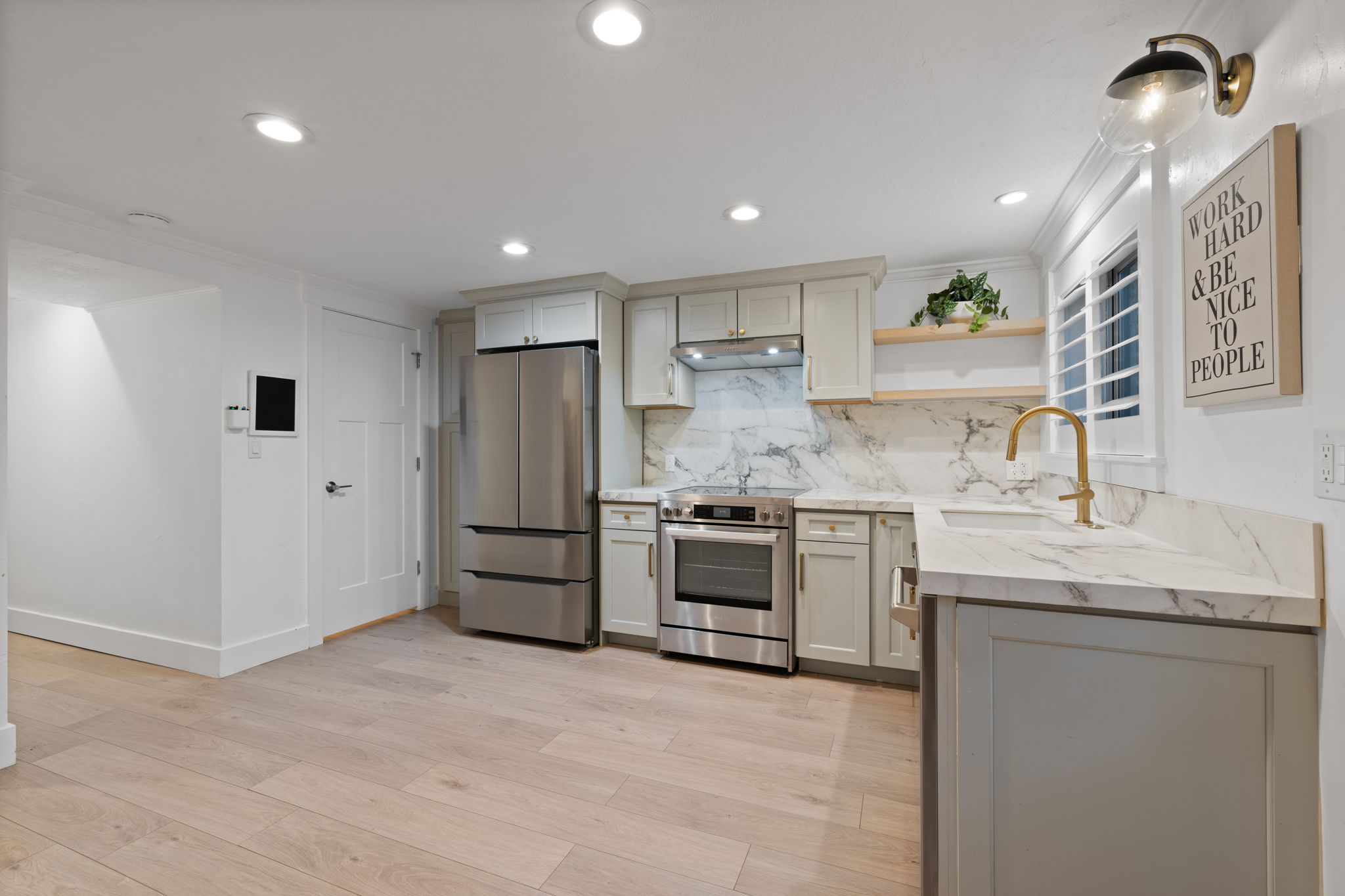 Kitchen featuring stainless steel appliances, light-toned cabinetry, wood-finish flooring, recessed lighting, and a white countertop with a veined pattern