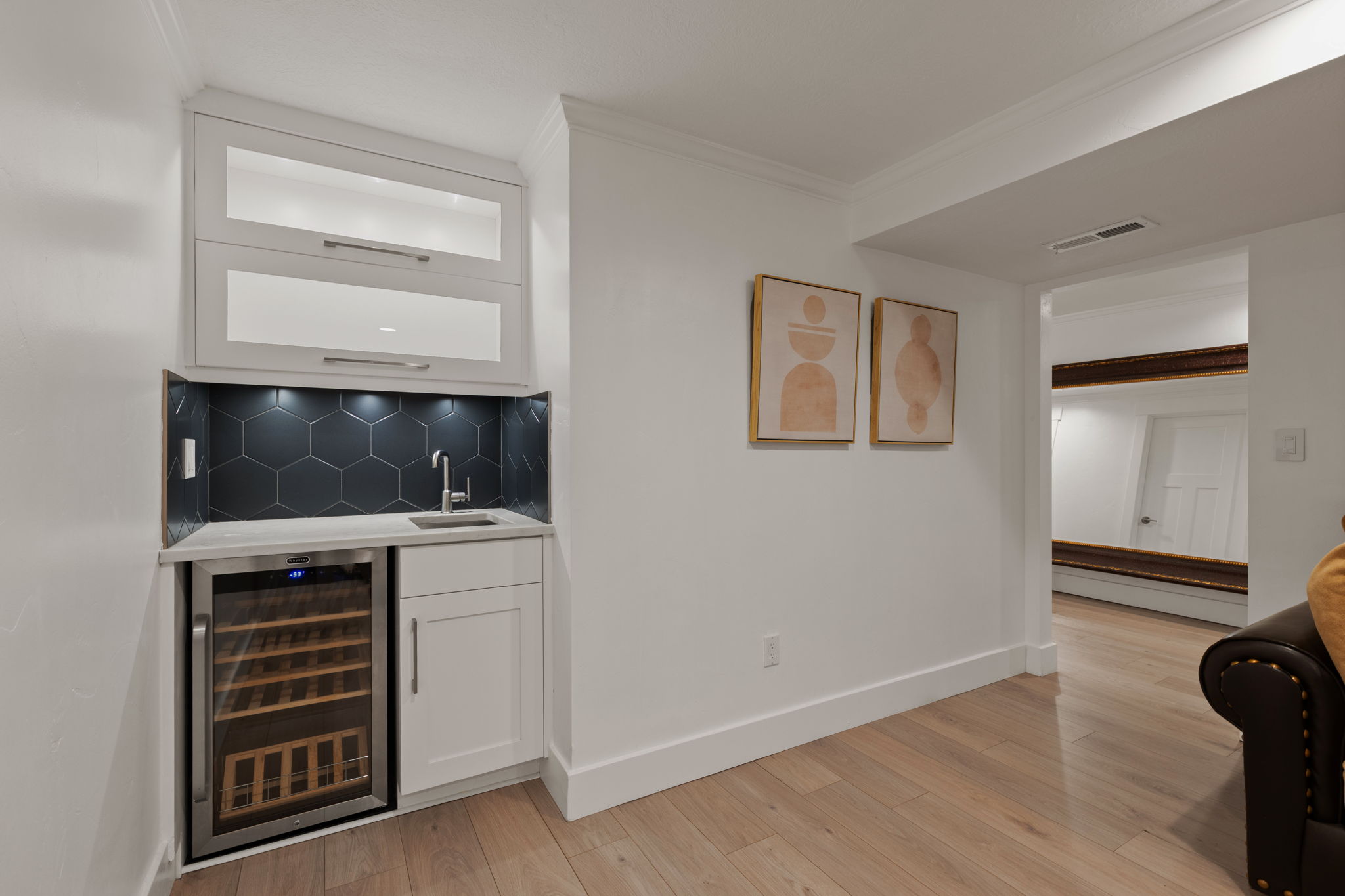 Built-in wet bar featuring white shaker cabinetry, hexagonal dark tile backsplash, an under-mount sink with a gooseneck faucet, and a wine refrigerator
