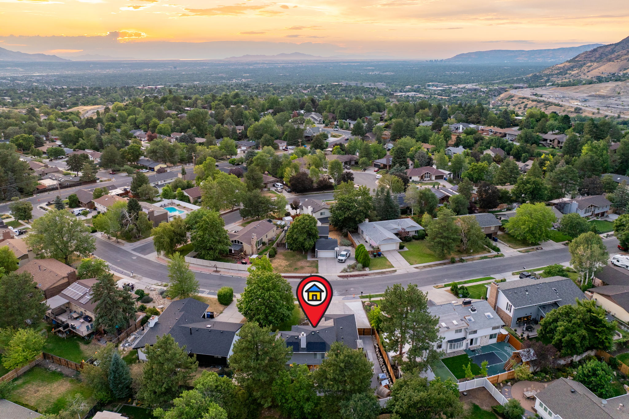 Aerial perspective of a verdant neighborhood with established trees and mountain backdrop