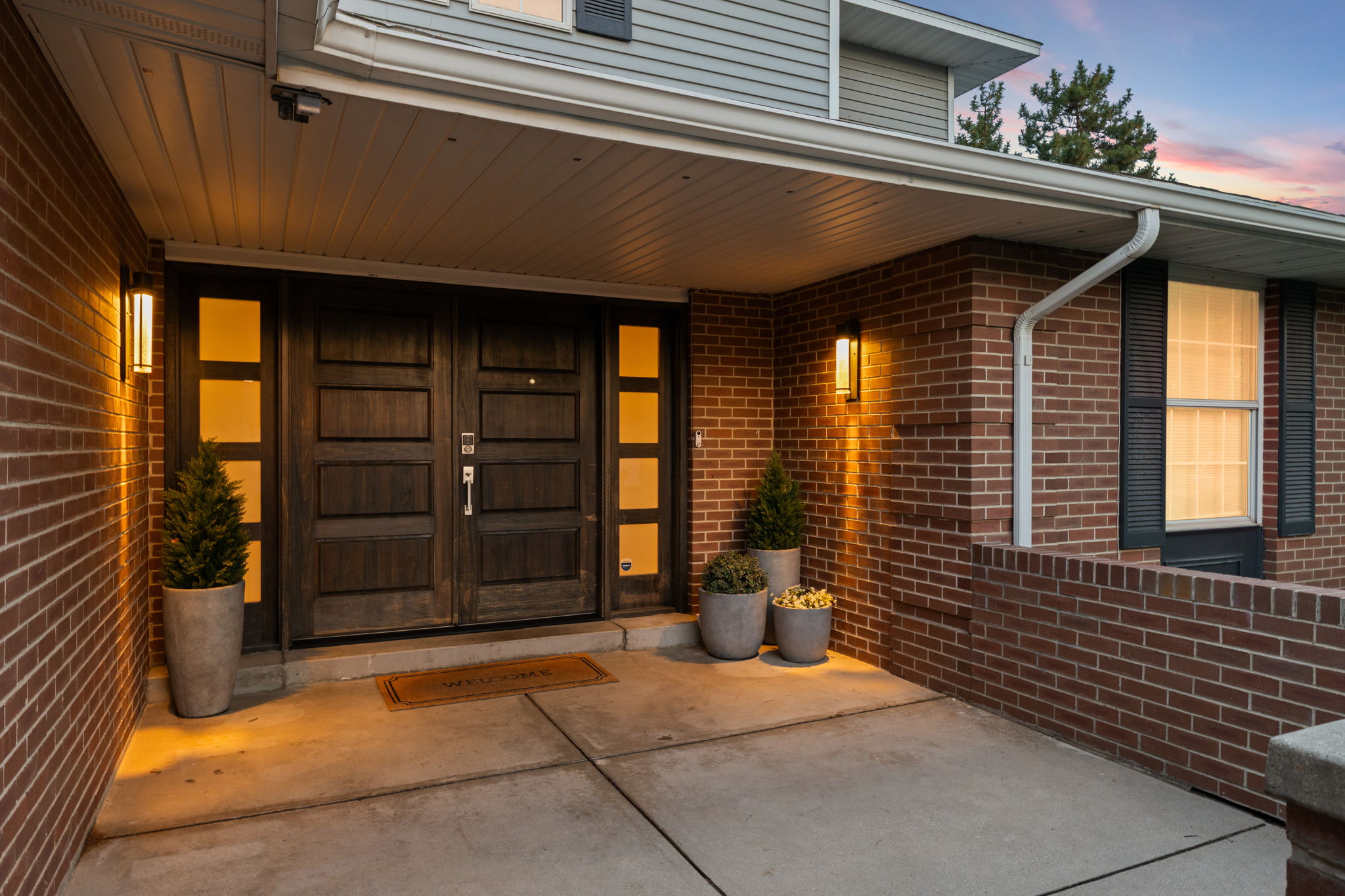 Entryway featuring double wood-paneled doors with frosted glass inserts, brick facade, and gray siding