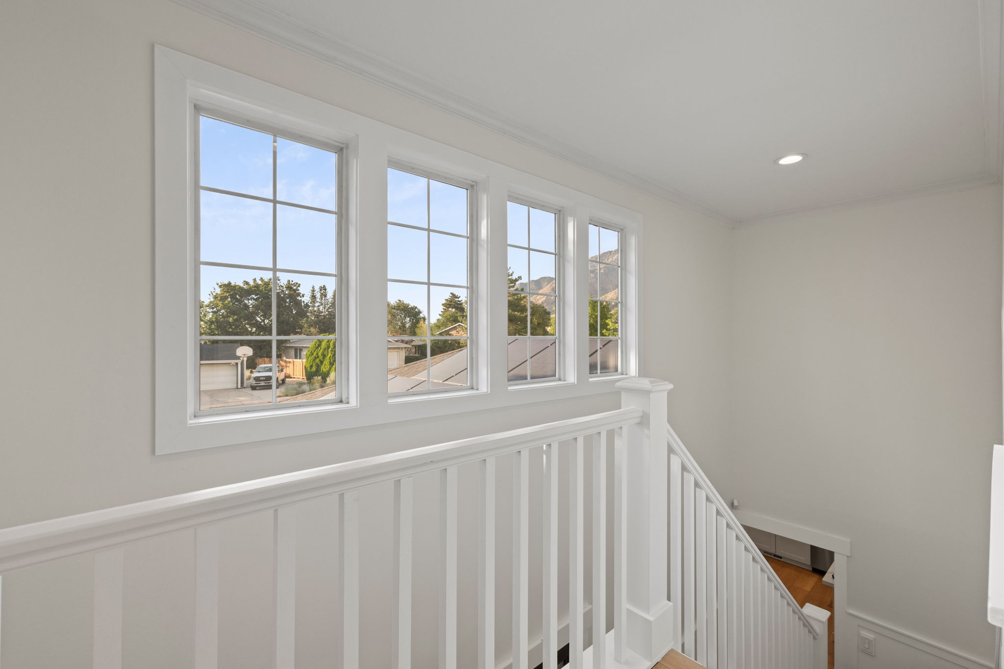 Staircase landing featuring a white balustrade and four gridded windows providing ample natural light