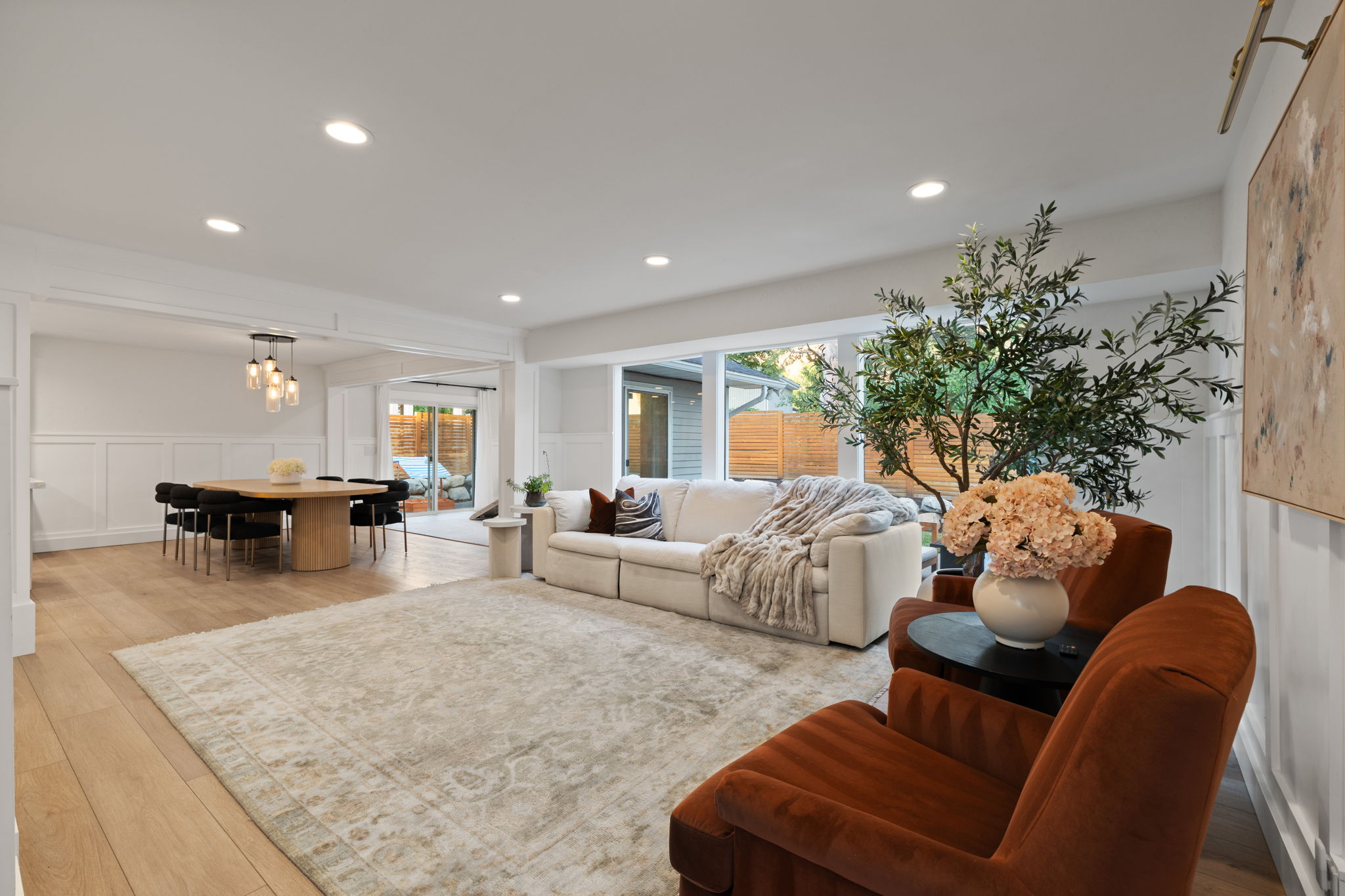 Open-concept living area featuring light wood-finish flooring, recessed lighting, and a dining space with a contemporary chandelier