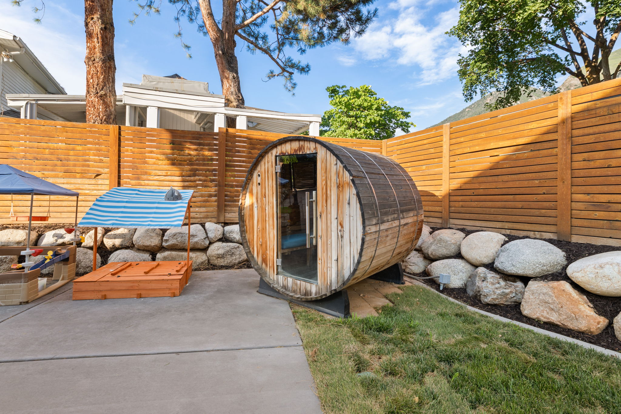 Barrel-shaped outdoor structure positioned on a concrete patio with an adjacent landscaped rock bed